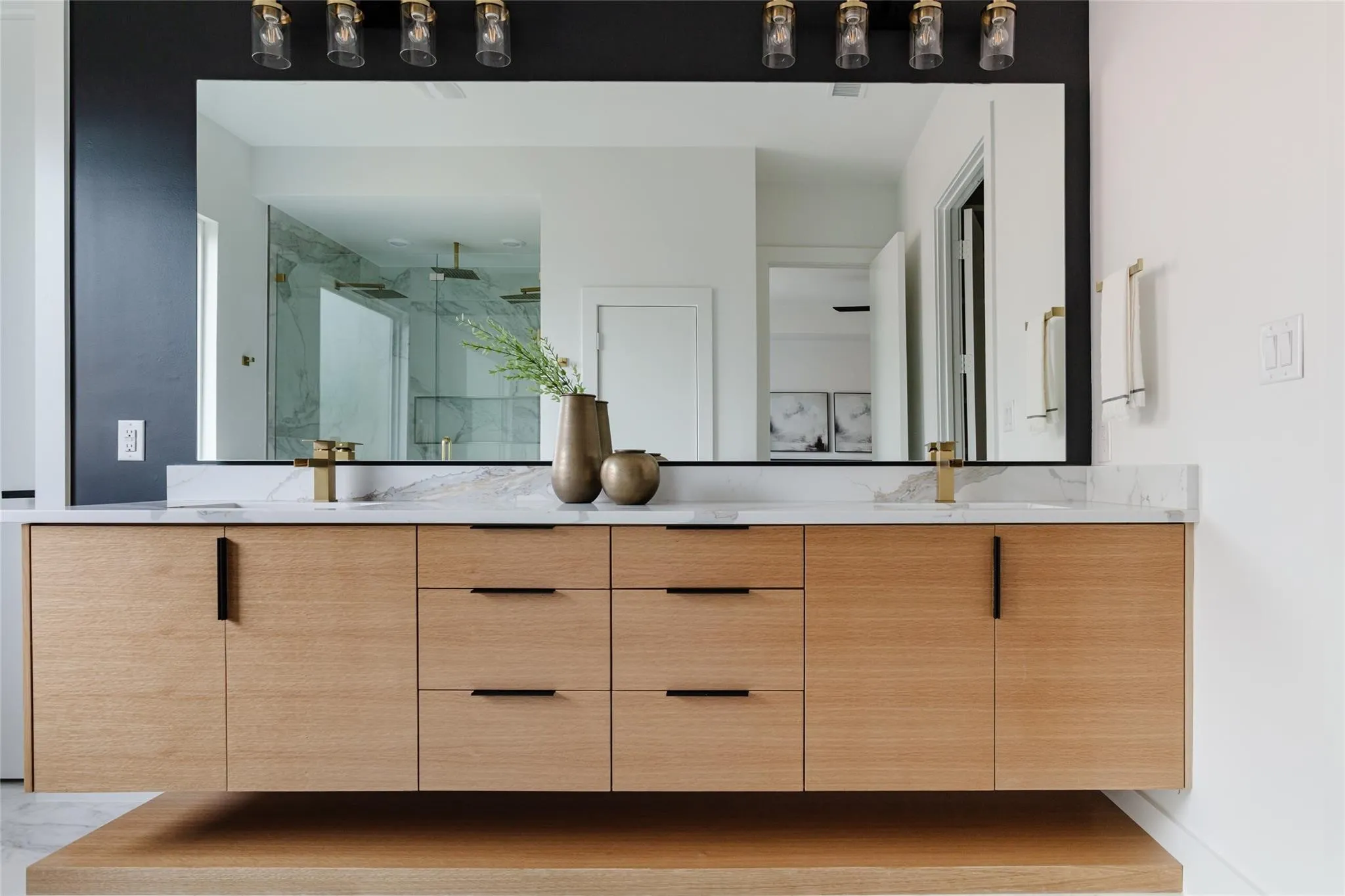Floating wood-finish vanity with ample storage, integrated sinks, and polished gold-tone fixtures