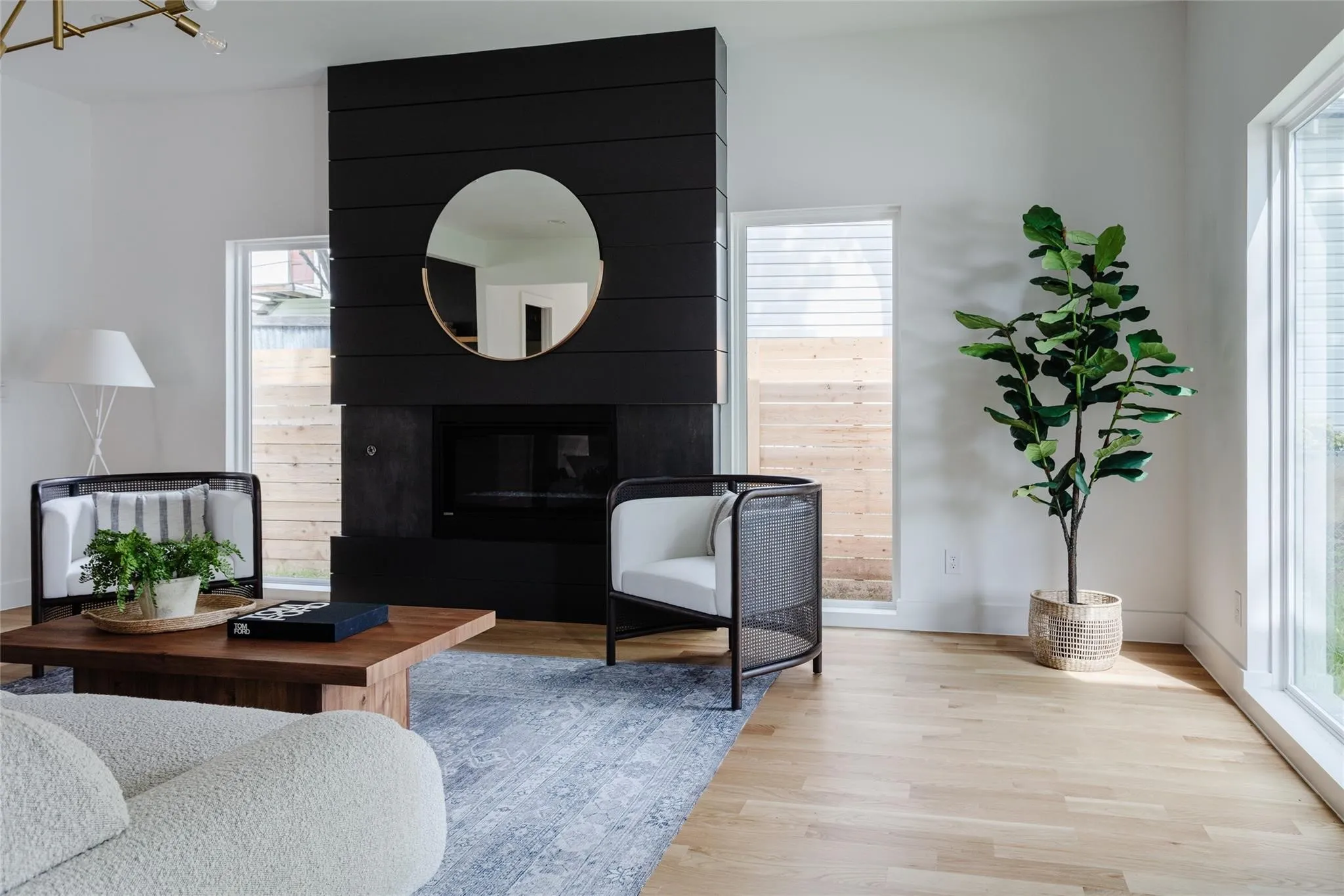 Black shiplap fireplace with a dark firebox, light wood-finish flooring, and expansive windows