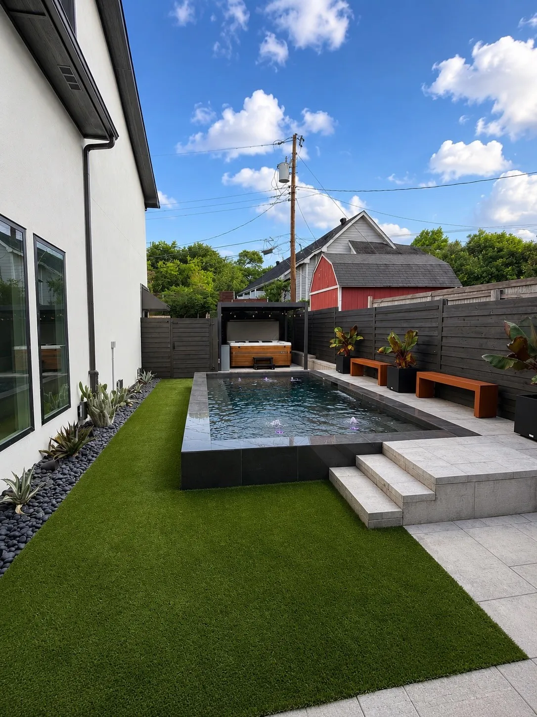 Contemporary backyard featuring a rectangular pool with dark tile surround, integrated steps, and surrounding patio pavers