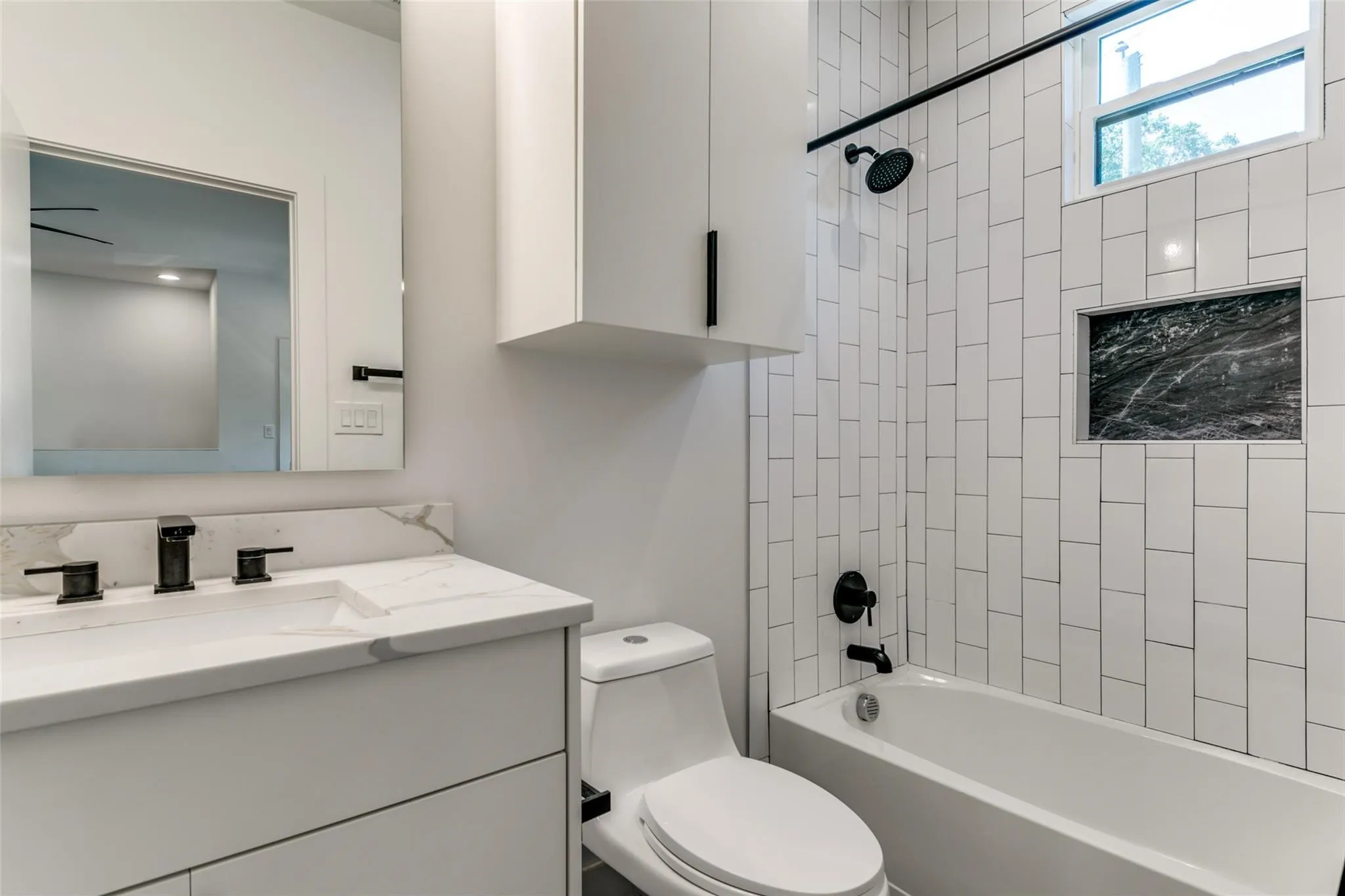 Guest Quarters Bath Modern vanity with integrated sink, black fixtures, and quartz-finish countertop