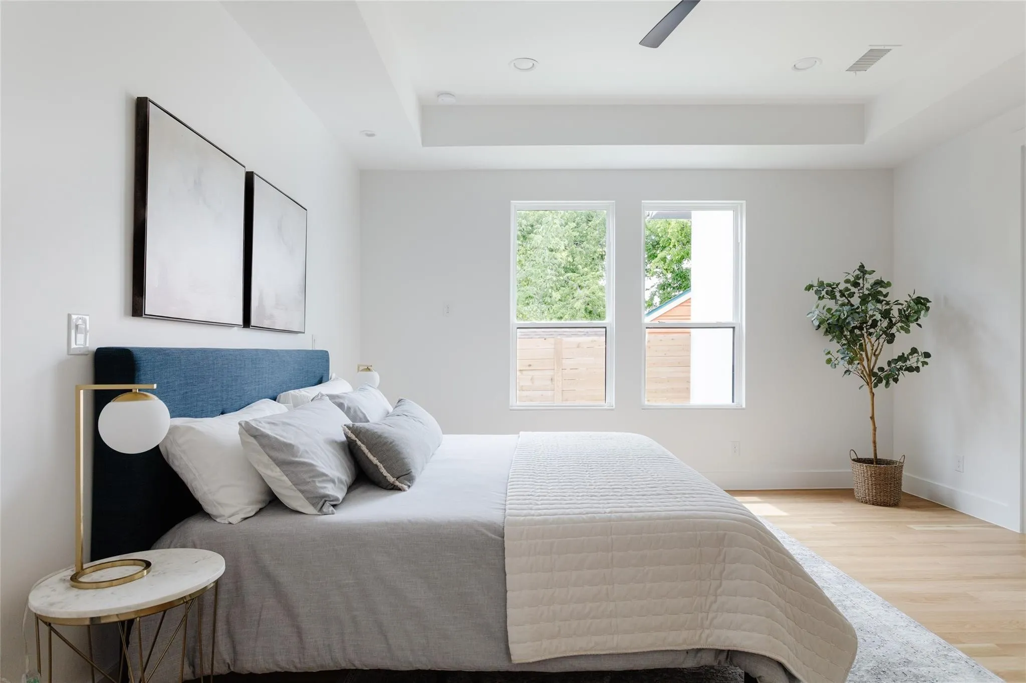Recessed lighting, light wood-finish flooring, tray ceiling, two windows, and a ceiling fan