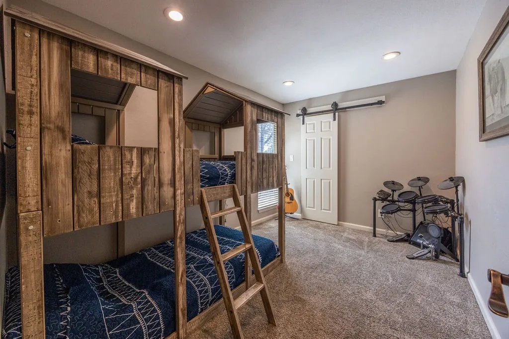 Custom built-in bunk beds with wood paneling, recessed ceiling lighting, textured carpeting, and a white barn door
