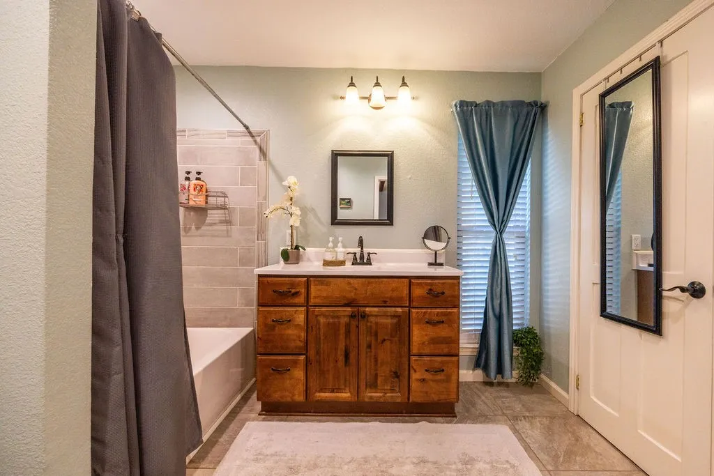 Wood-finish vanity with white countertop, chrome faucet, and rectangular mirror