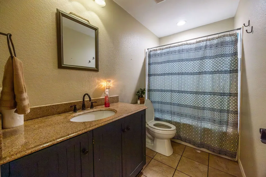 Vanity with an integrated sink, dark wood-finish cabinetry, and a stone-finish countertop