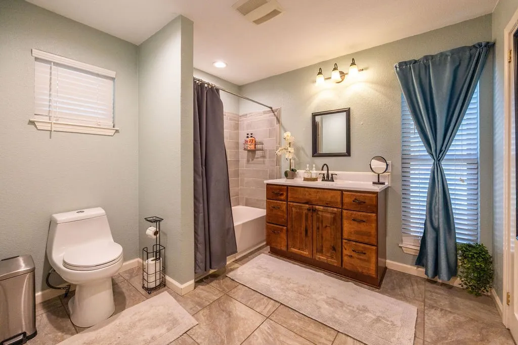 Wood-finish vanity with white countertop, undermount sink, and matte black faucet