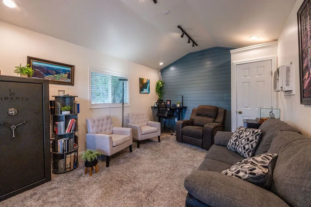 Sloped ceiling with track lighting, textured accent wall, and recessed lighting