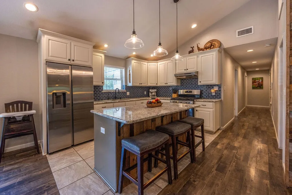 Kitchen featuring white cabinetry, stainless steel appliances, a tile backsplash, and an island with a light-colored countertop