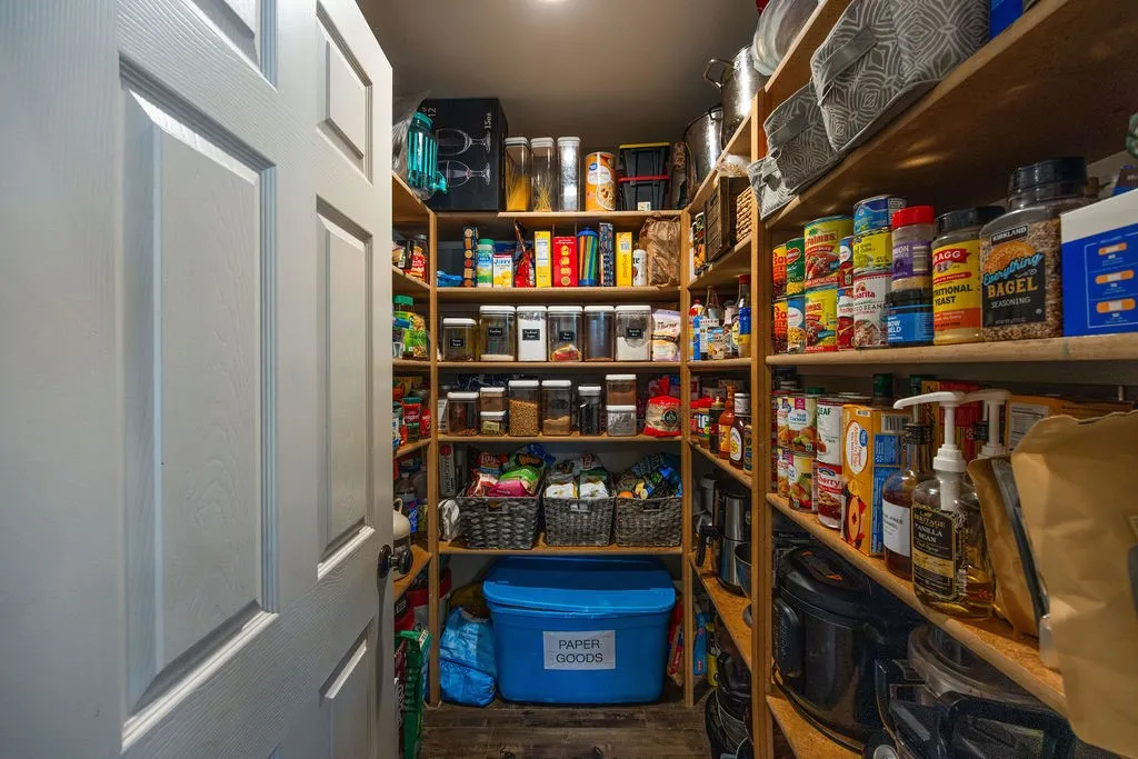 Walk-in pantry featuring extensive wood shelving, recessed lighting, and a paneled interior door