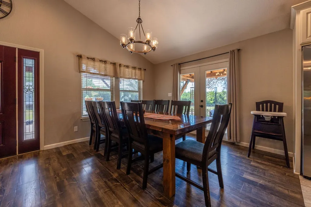 Vaulted ceiling, wood-finish flooring, decorative entryway door with sidelight, double french doors, and a chandelier lighting fixture
