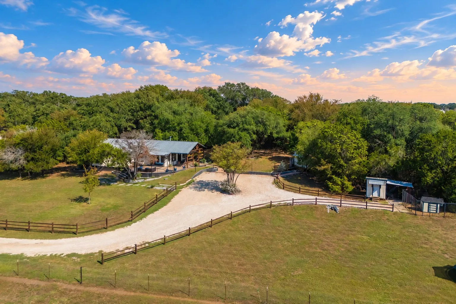 Expansive gravel driveway leading to the property, surrounded by a wood-rail fence