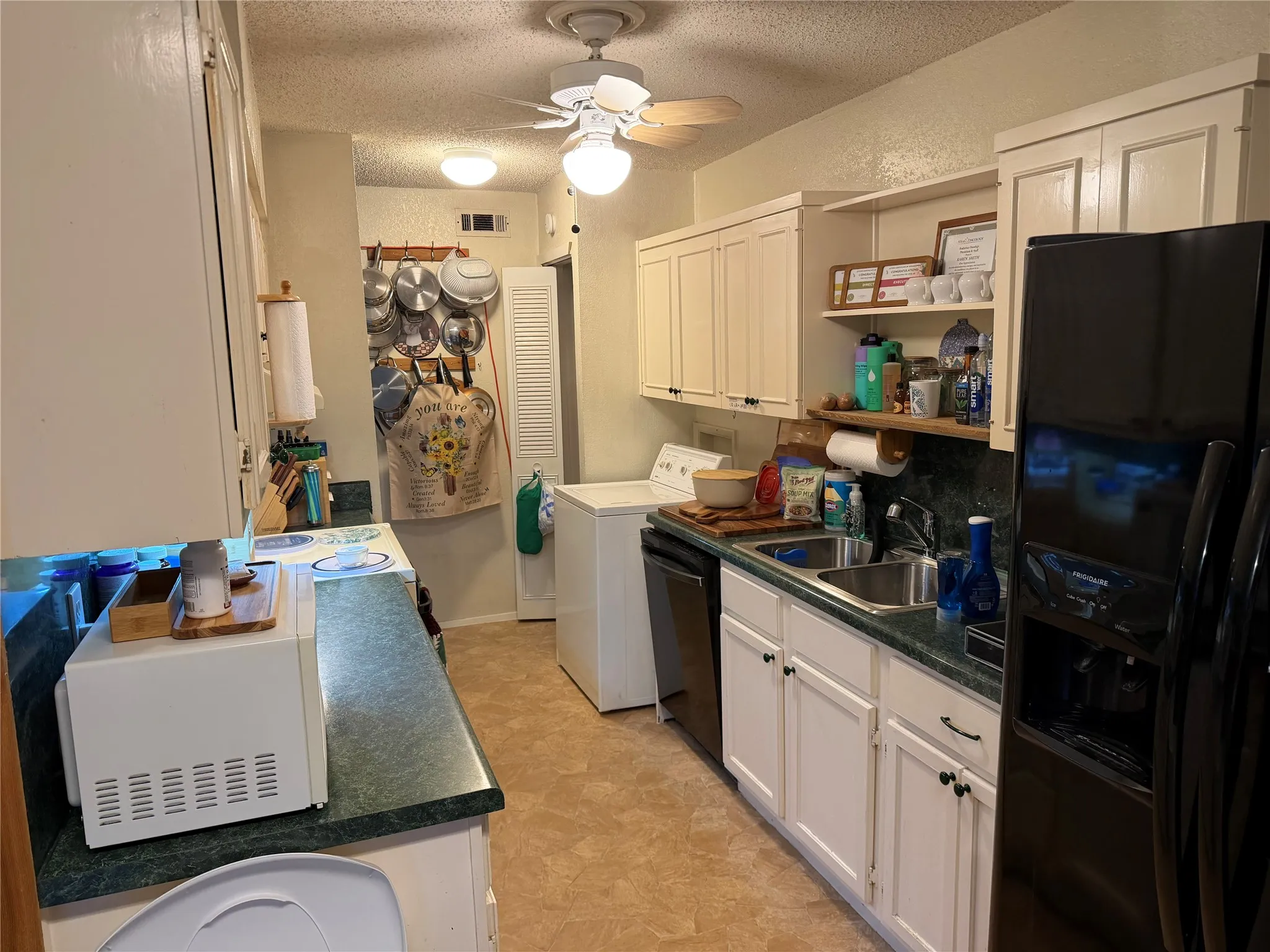 Kitchen featuring white cabinetry, a double basin sink, and a black side-by-side refrigerator