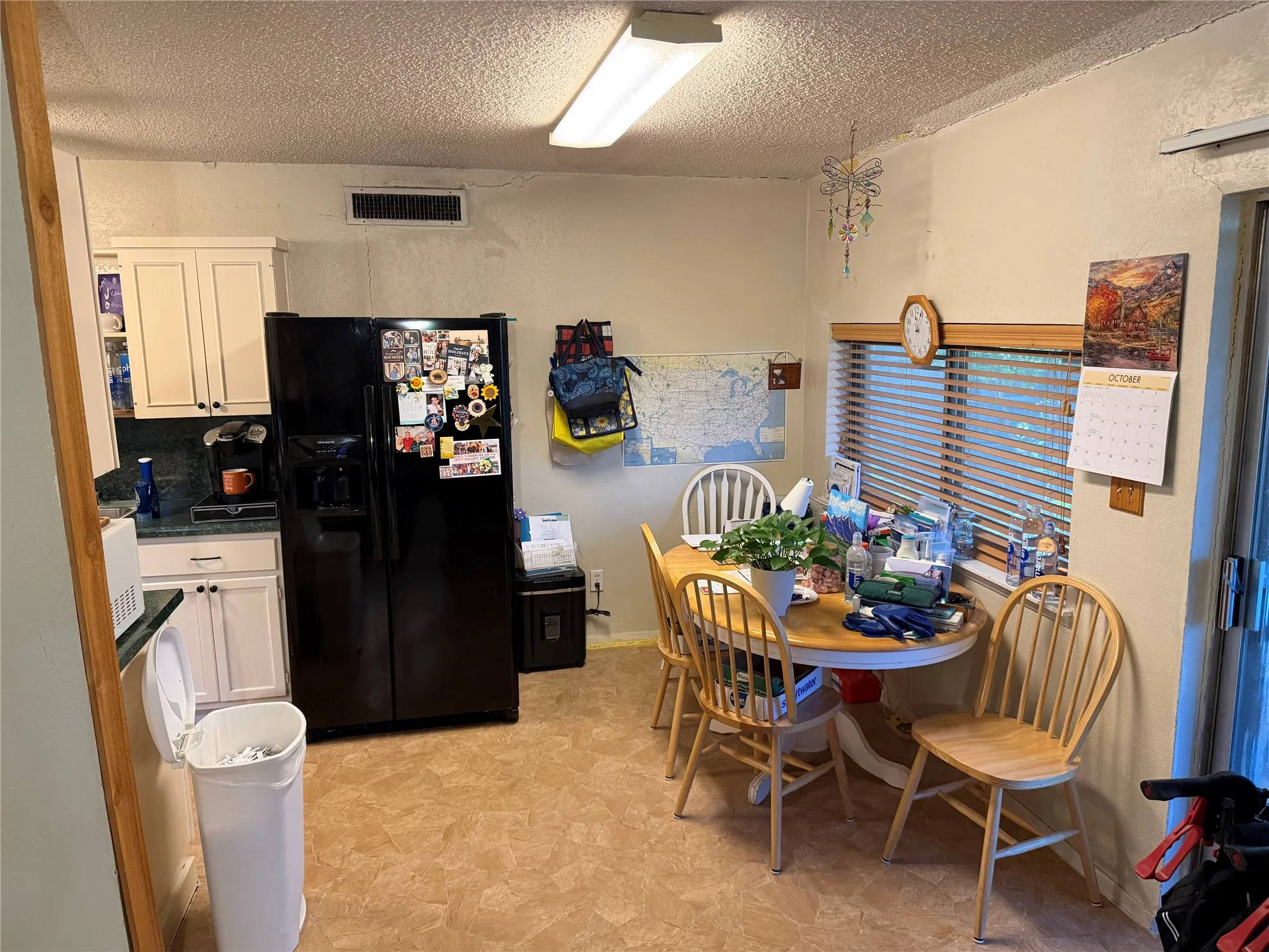 Kitchen with white cabinetry, dark countertop, and integrated refrigerator