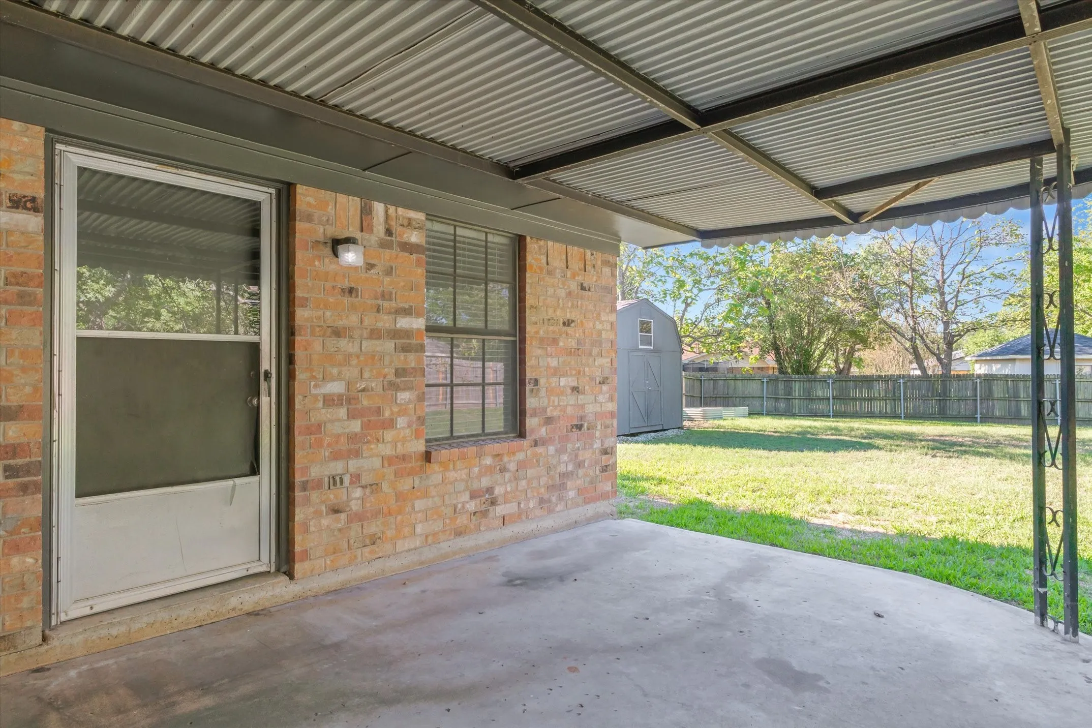 Covered patio overlooks a shaded backyard