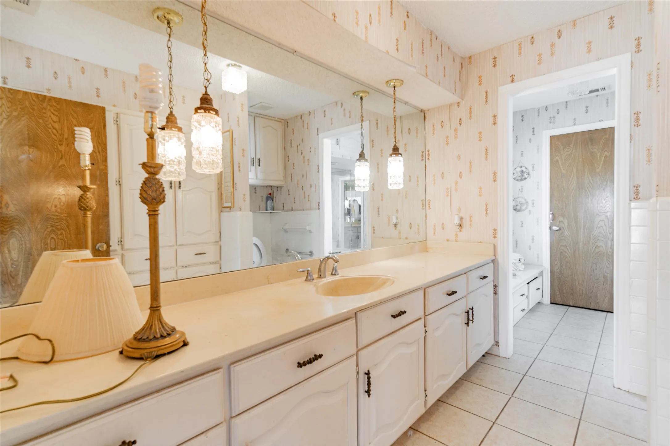 Vanity with an integrated sink, full-width mirror, and pendant lighting