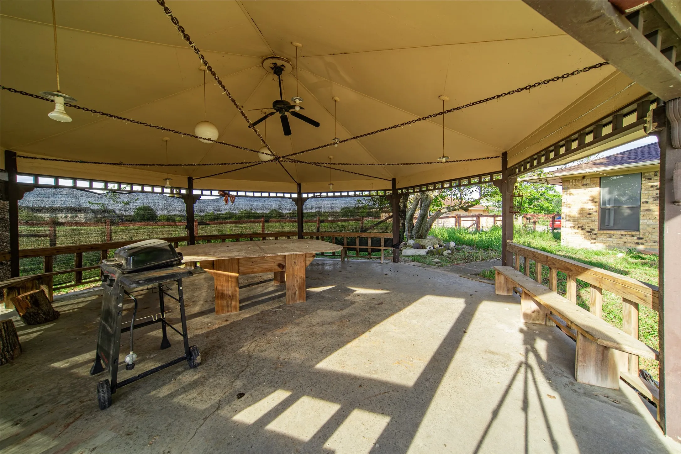 Covered outdoor pavilion with concrete flooring, wood perimeter railing, and a canvas roof