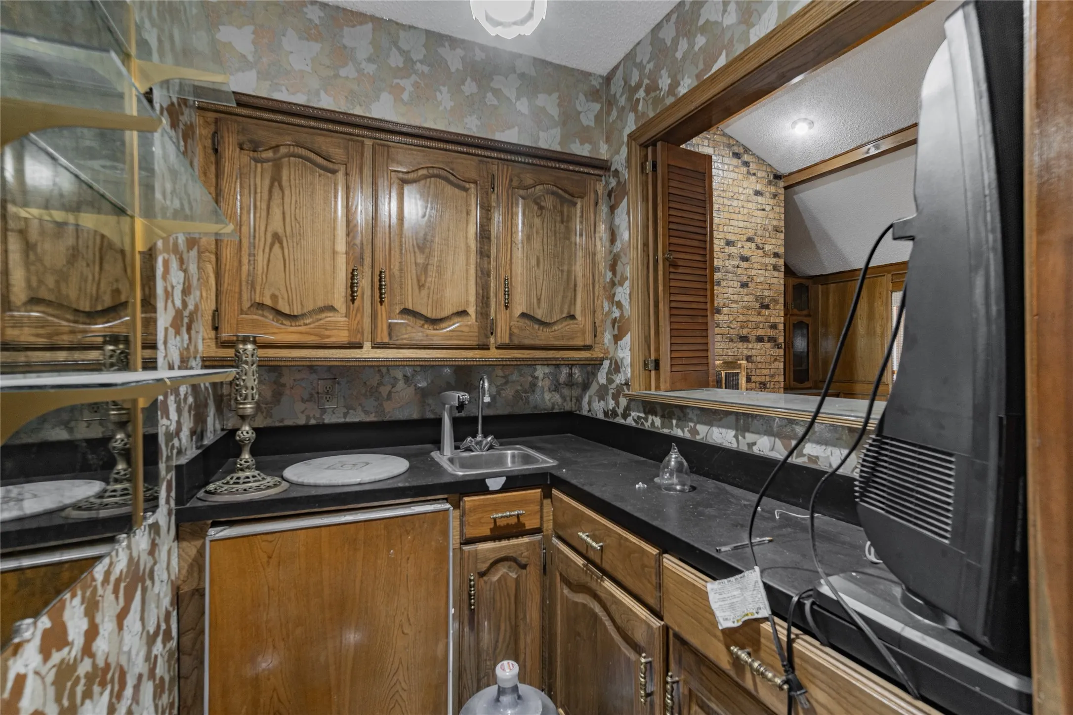 Wood cabinetry with black countertops, integrated sink, and pass-through window
