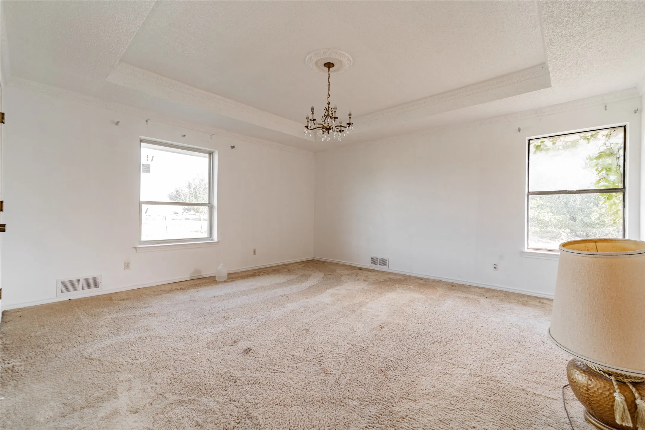 Tray ceiling with crown molding, decorative ceiling medallion, and a chandelier