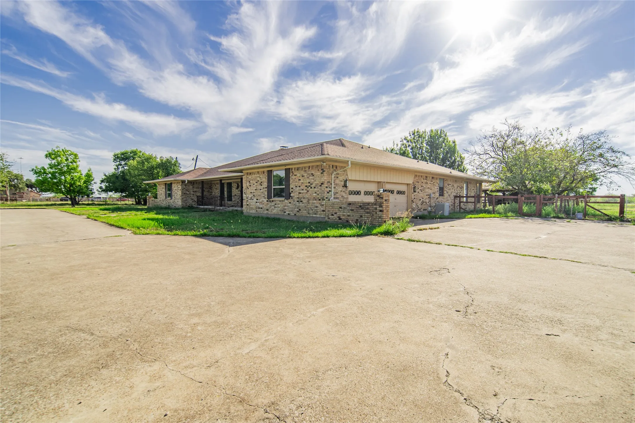 Brick exterior residence featuring a two-car garage, concrete driveway, and a fenced perimeter