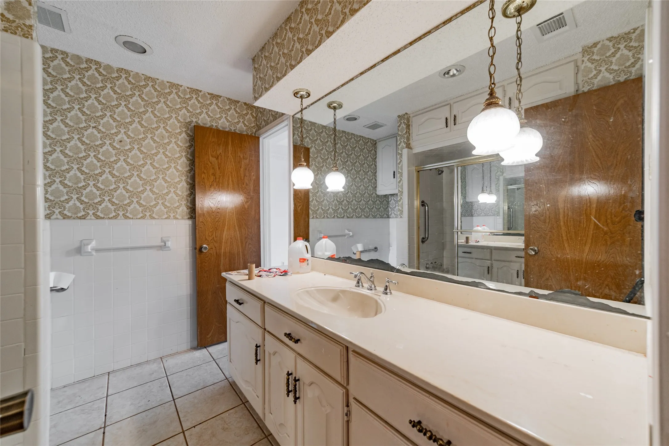 Integrated vanity with single basin, tile flooring, and a shower enclosure