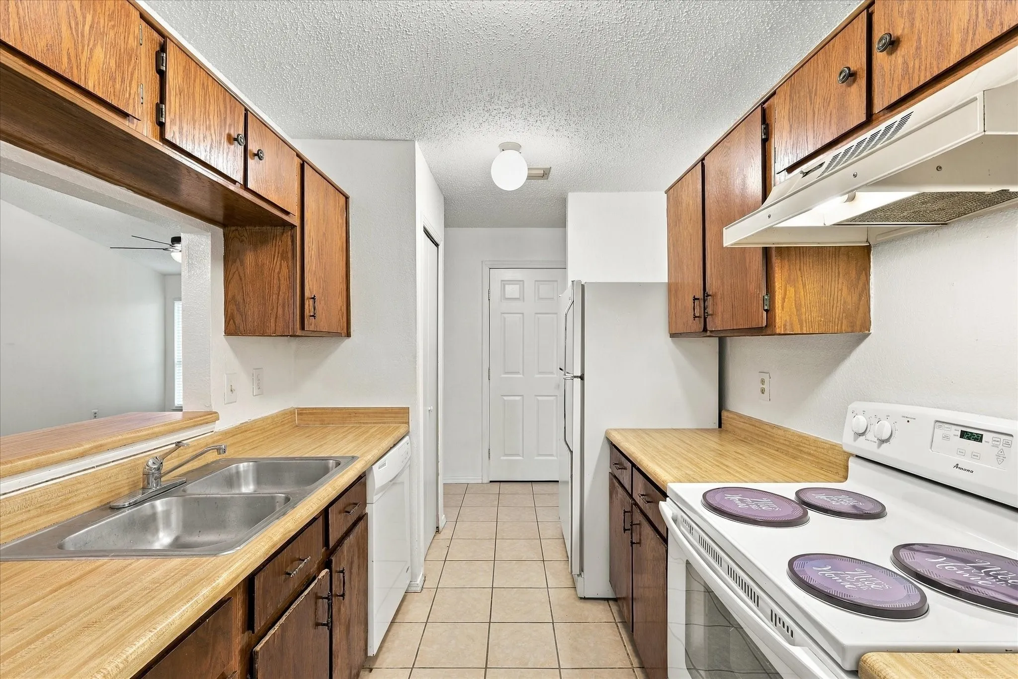 Galley kitchen featuring wood-finish countertops, wood cabinetry, and a double basin stainless steel sink