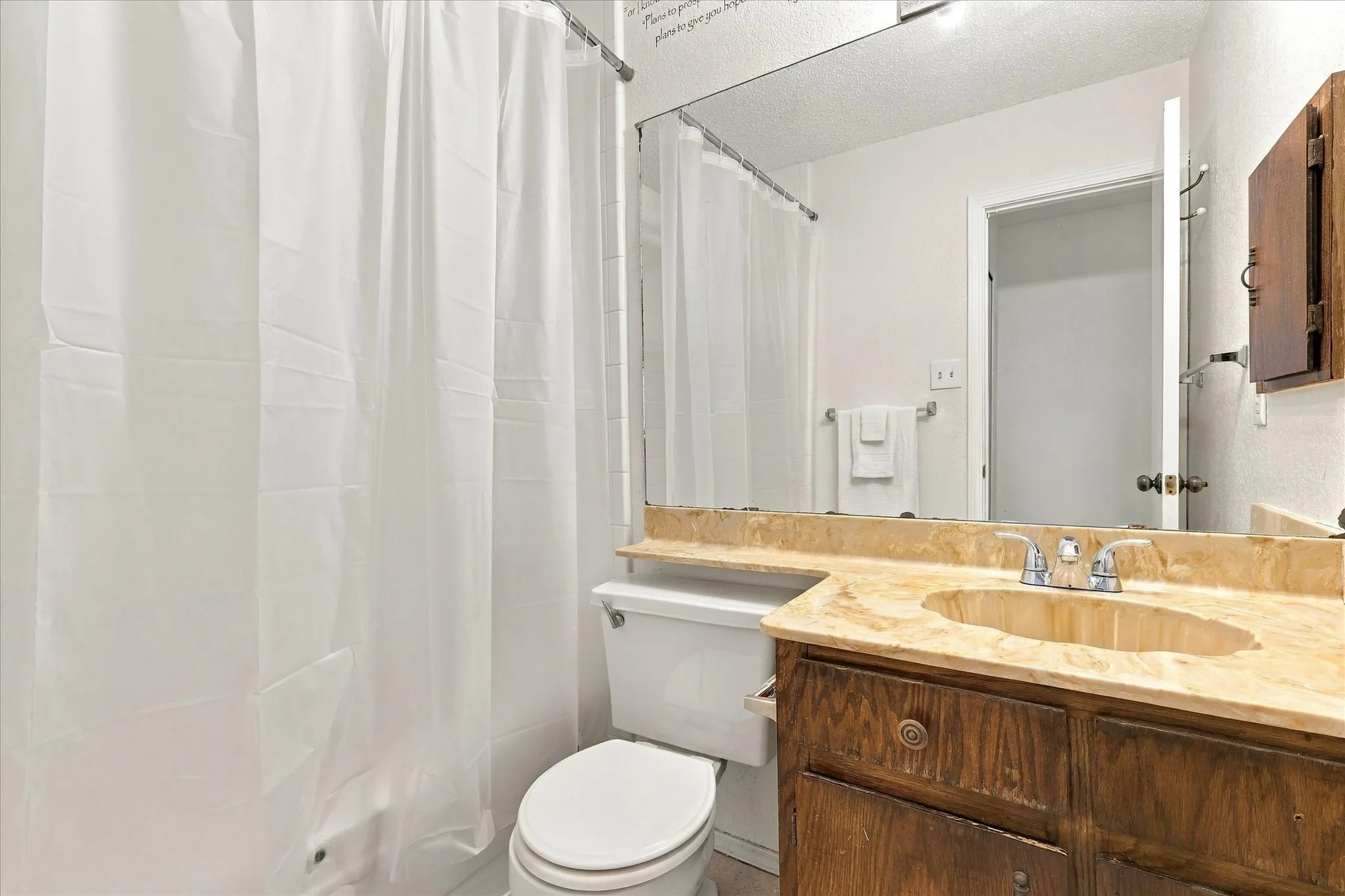 Bathroom with a stone-finish countertop, integrated sink, and wood-finish vanity cabinetry