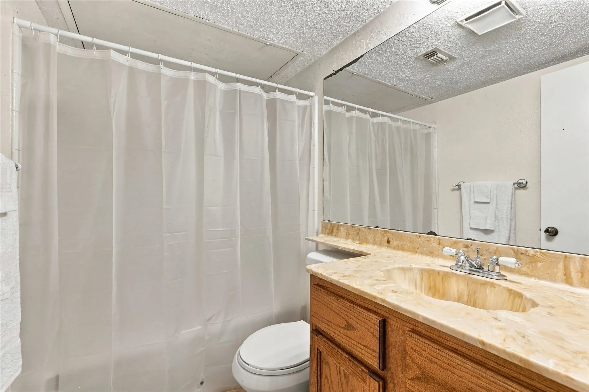 Vanity with light-toned countertop, undermount sink, and wood-finish cabinetry