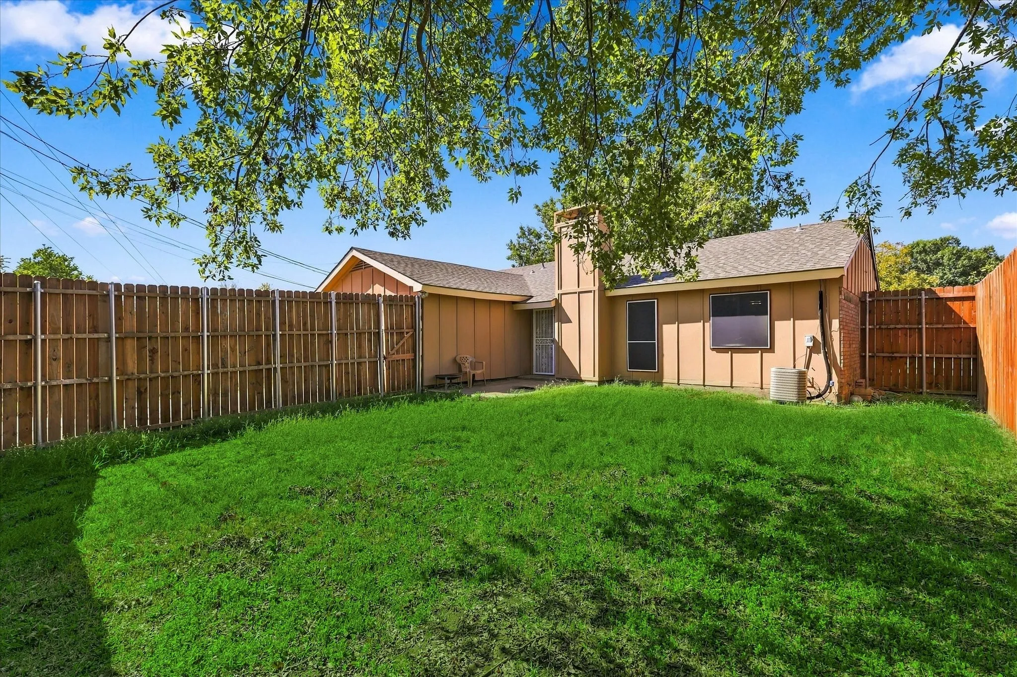 Expansive backyard featuring a lush lawn, privacy fencing, and mature trees