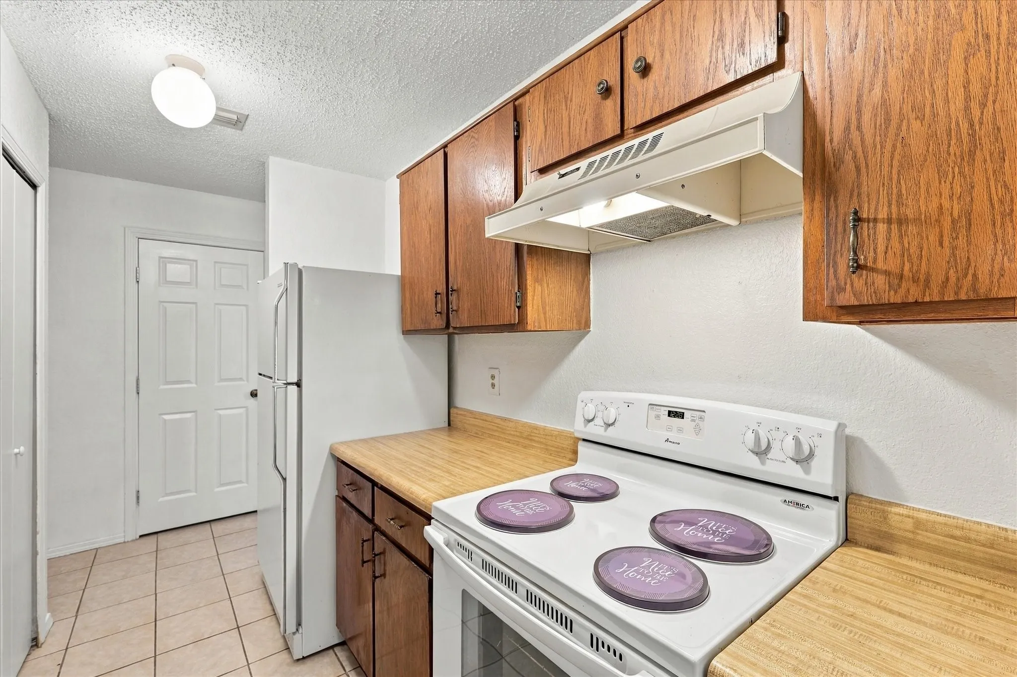 Kitchen featuring wood-finish cabinetry, laminate countertops, and tile flooring