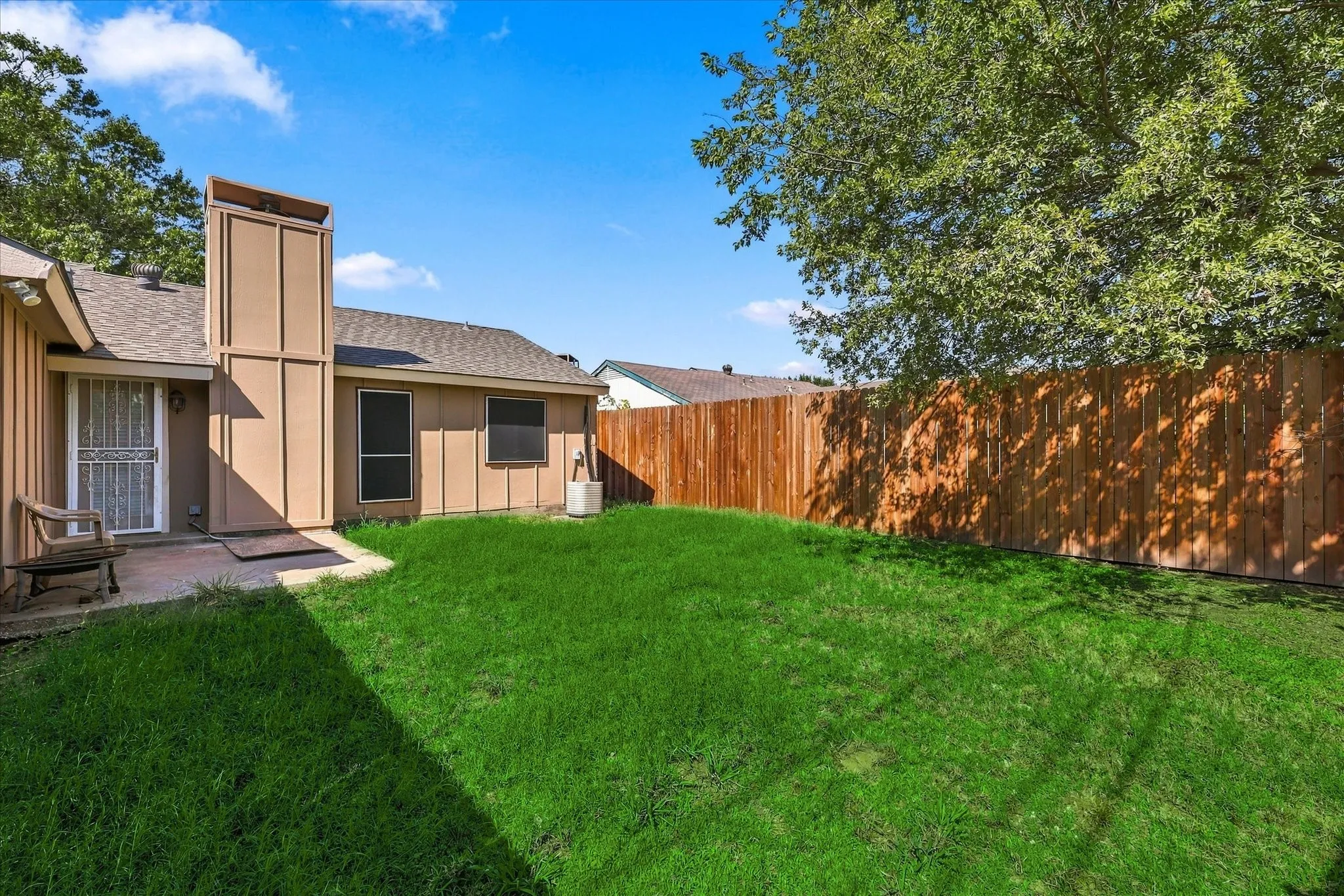 Expansive backyard featuring a manicured lawn, a full wood privacy fence, and a concrete patio