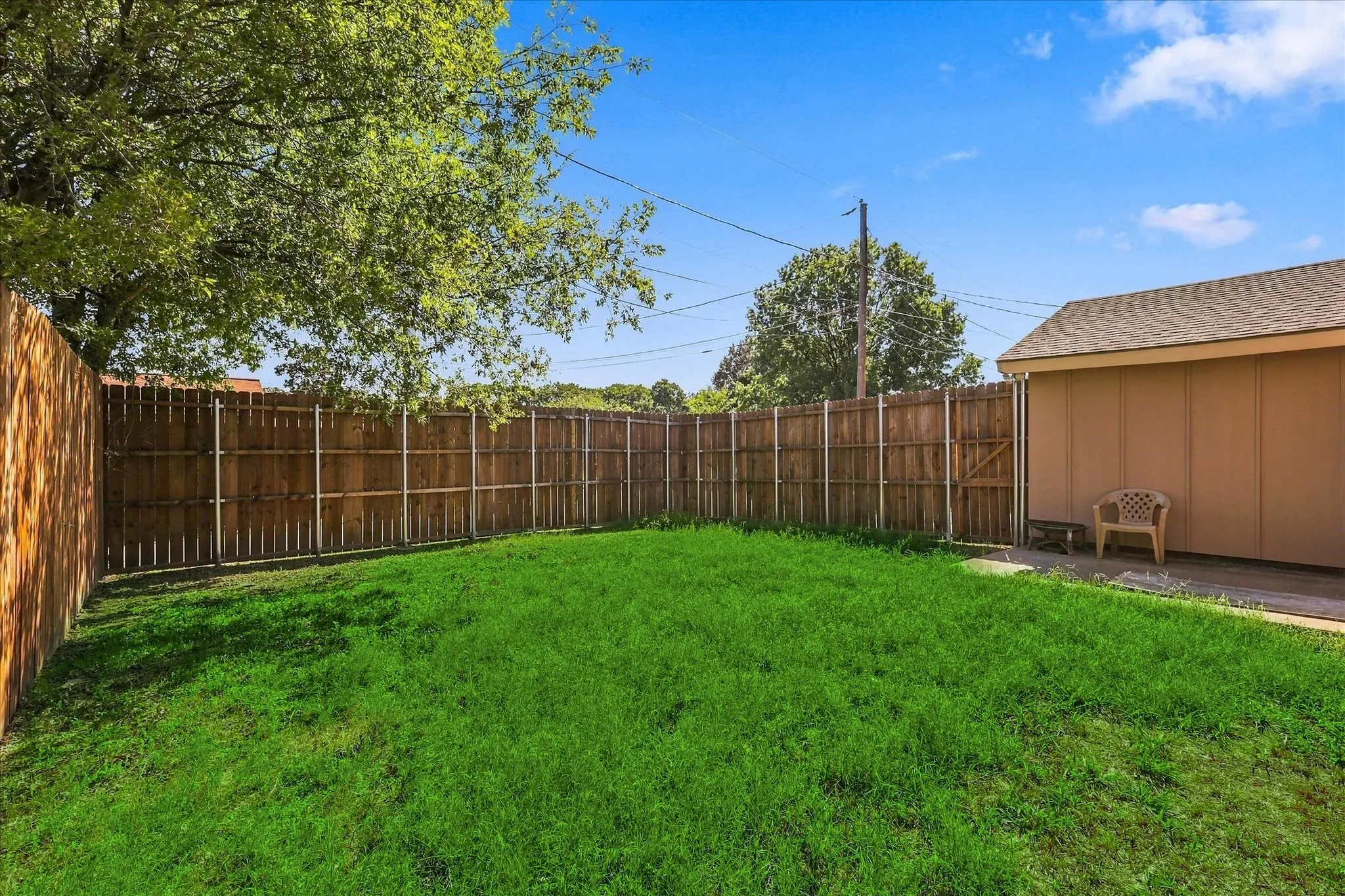 Expansive grassy area with wood fencing and a storage structure