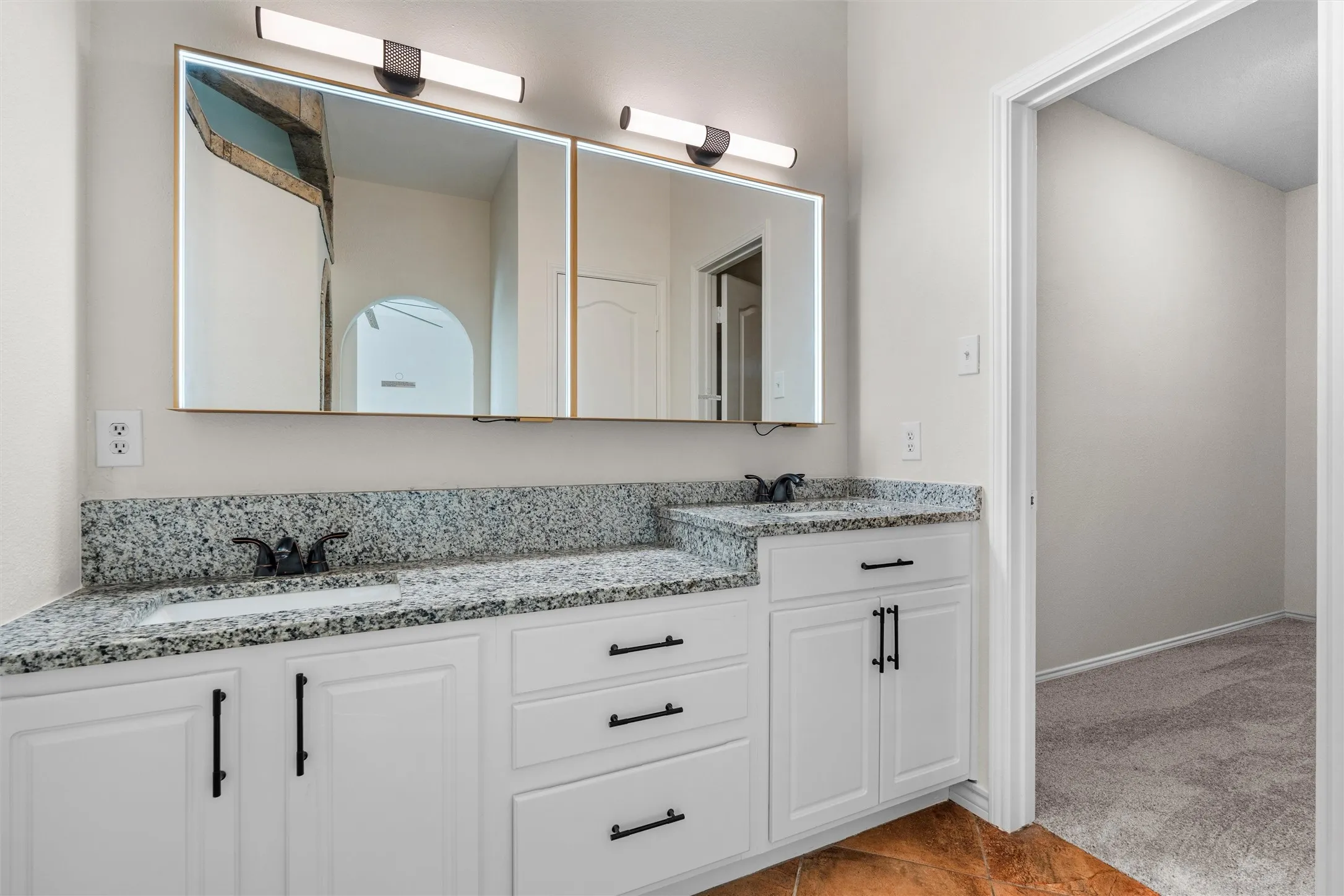 Dual vanity with white cabinetry and dark hardware