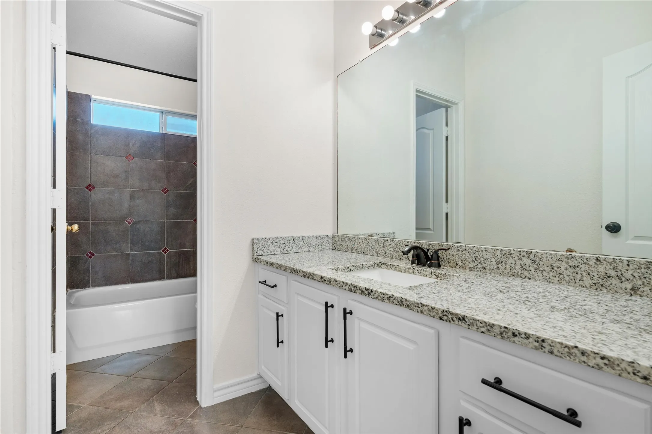 White vanity with dual sinks, speckled countertop, and dark hardware