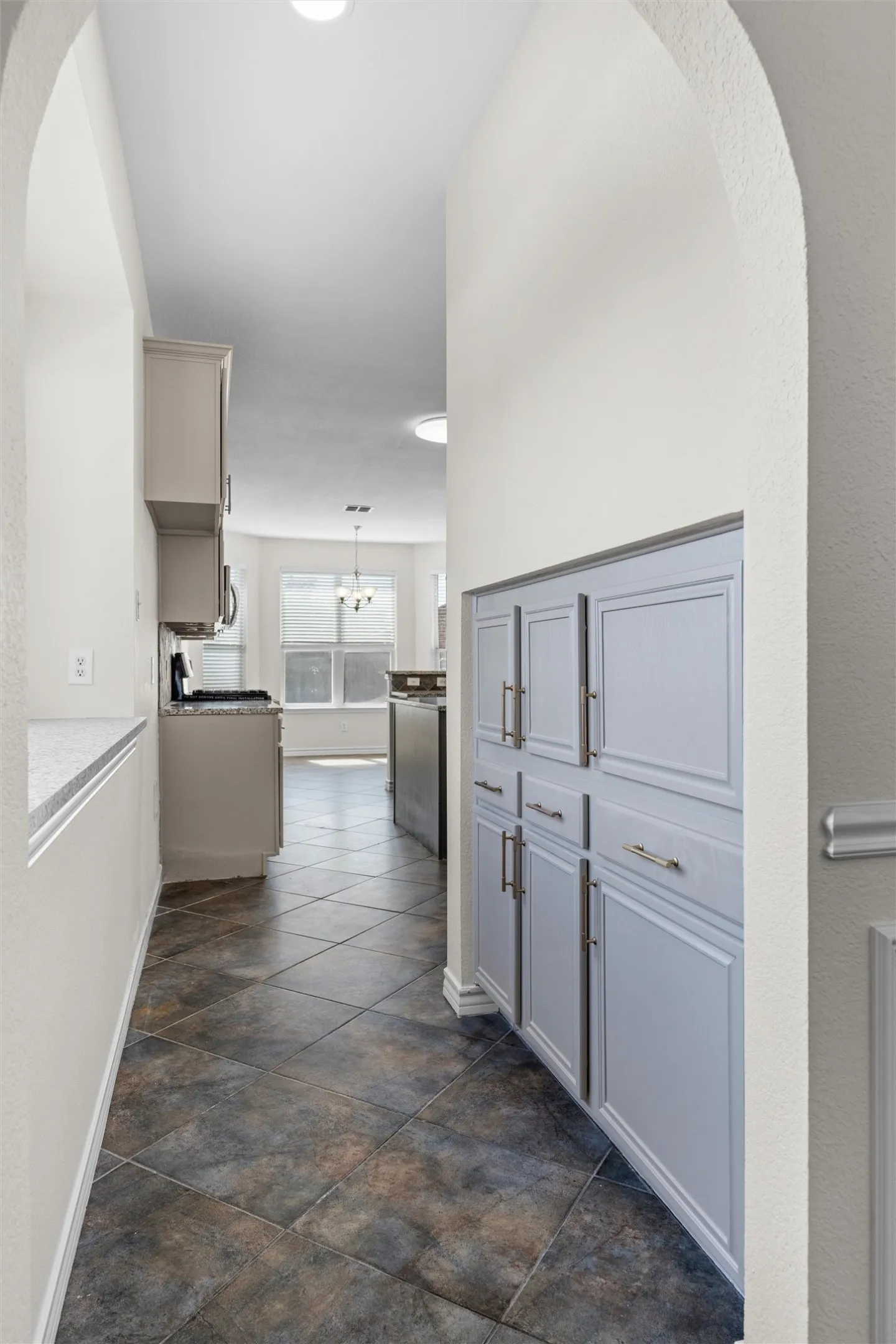 Archway entry featuring built-in cabinetry, tile flooring, and recessed lighting