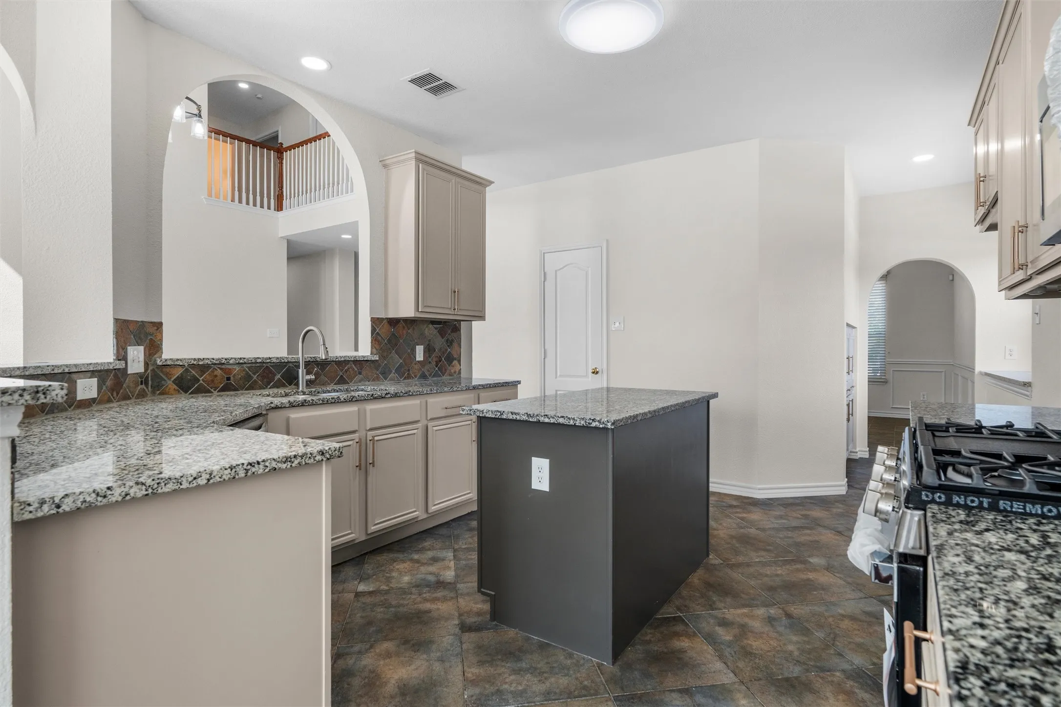 Kitchen featuring a central island, granite countertops, tile backsplash, stainless steel gas range, and recessed lighting
