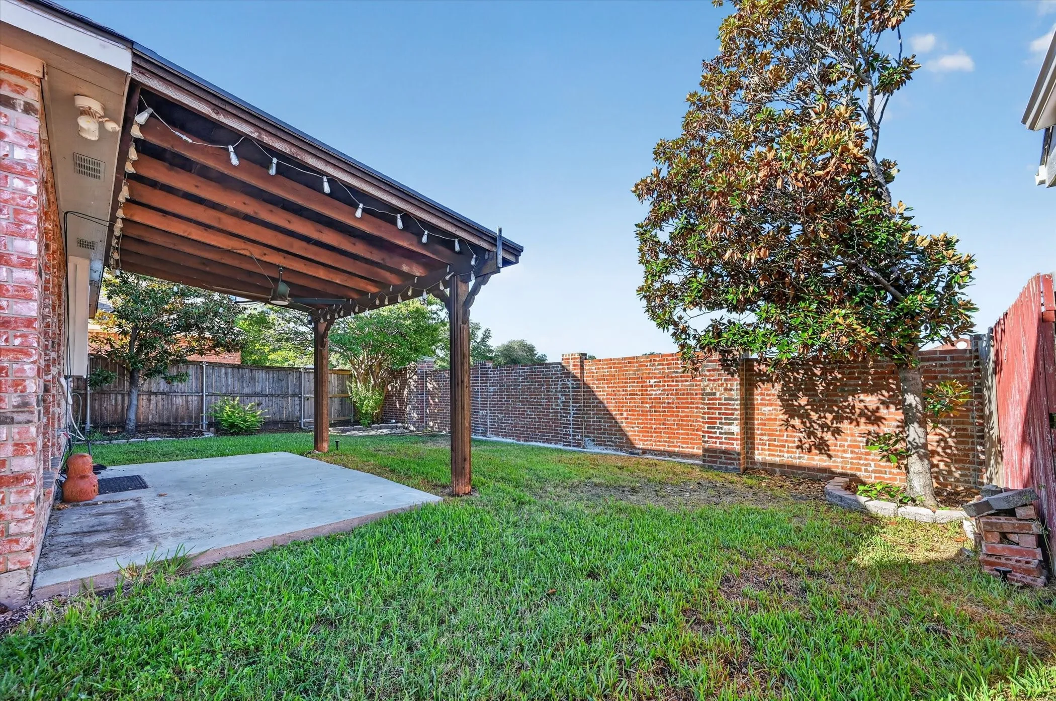 Covered patio featuring a wood-beam ceiling, concrete slab, and brick exterior