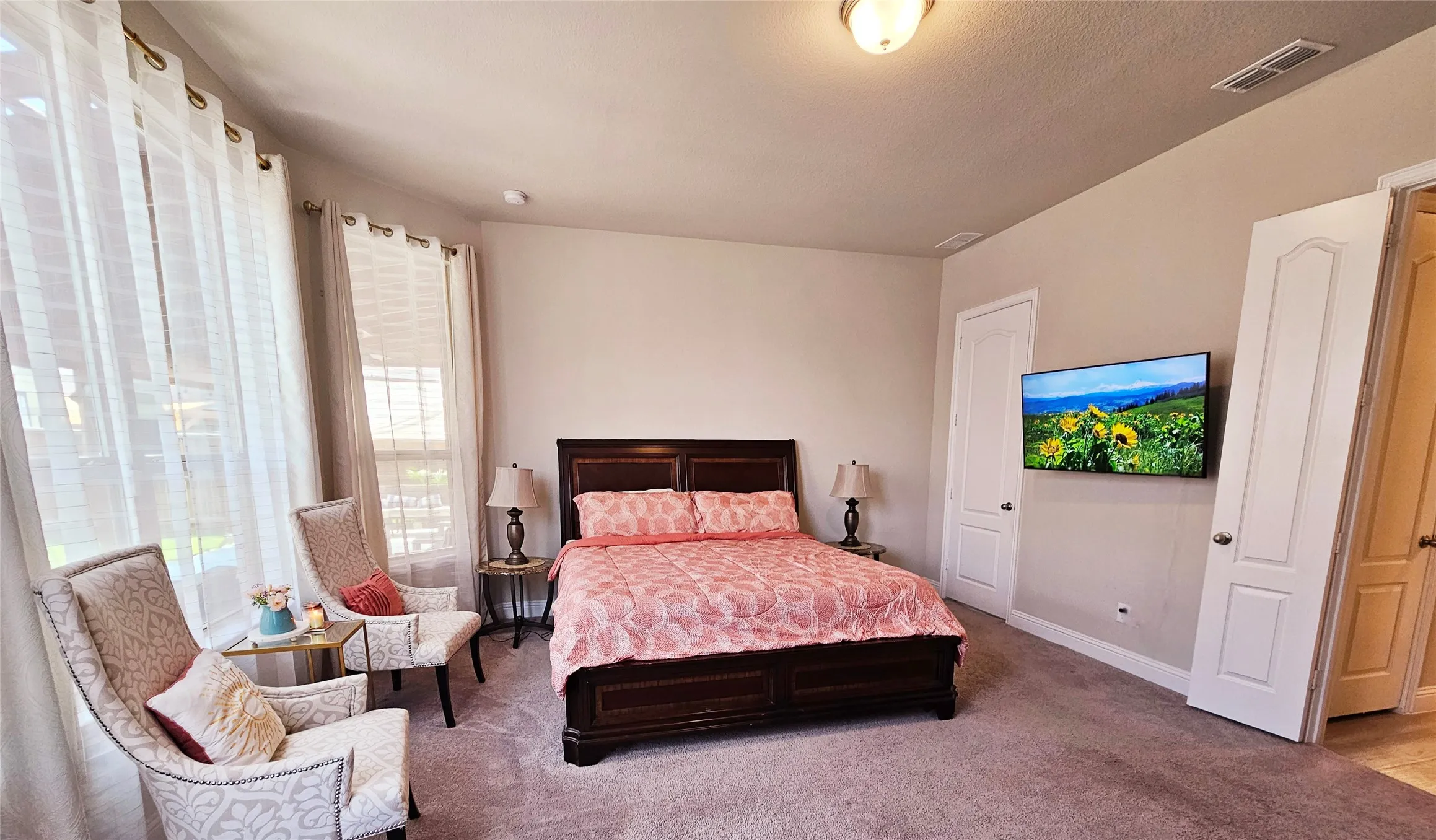 Spacious room featuring carpeted flooring, multiple windows, a ceiling-mounted light fixture, and two white panel doors
