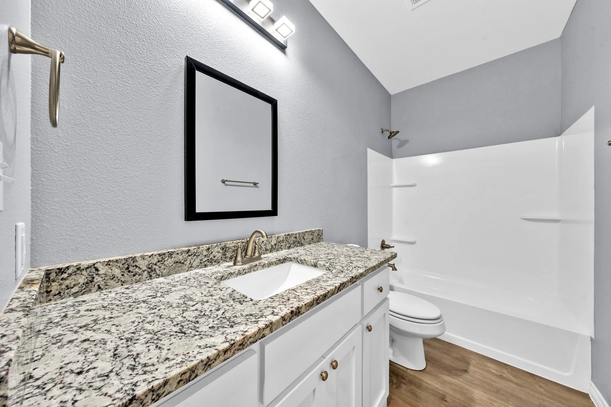 White vanity with granite-style countertop, undermount sink, and brushed nickel faucet
