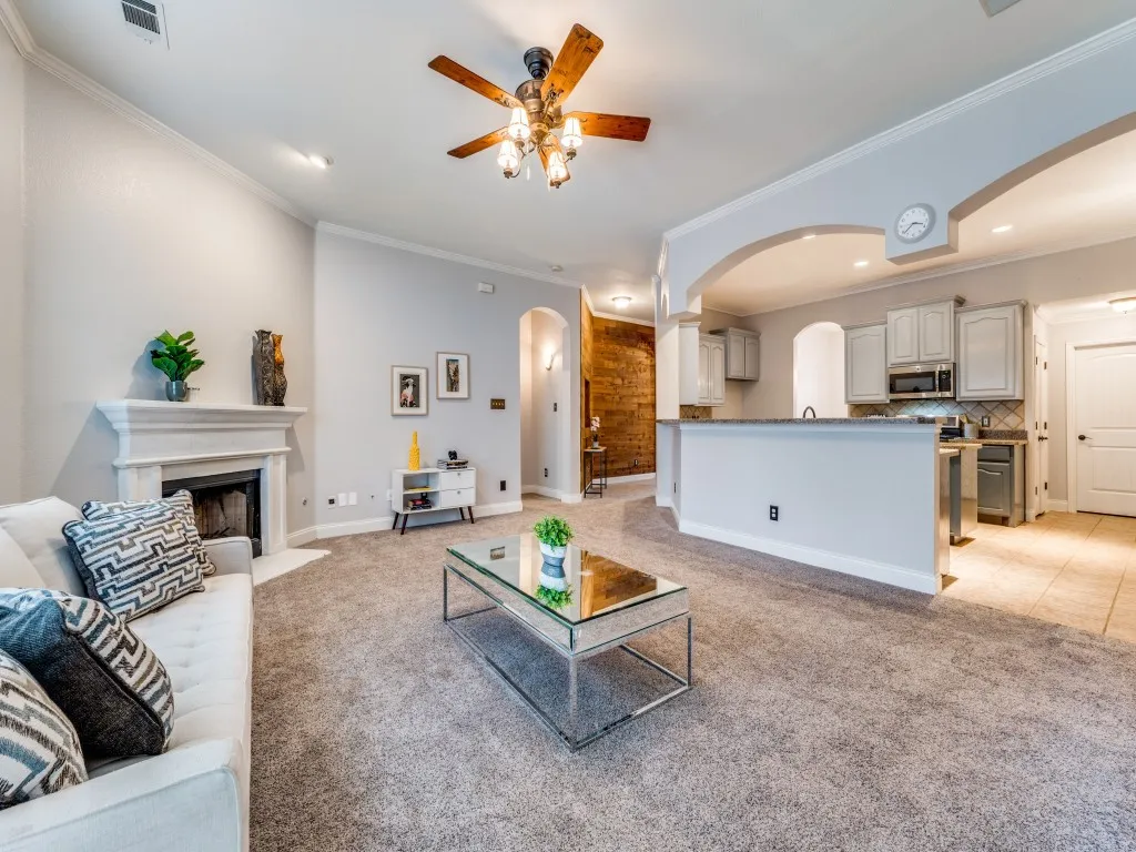 Living area featuring a fireplace with a mantel, crown molding, and a ceiling fan