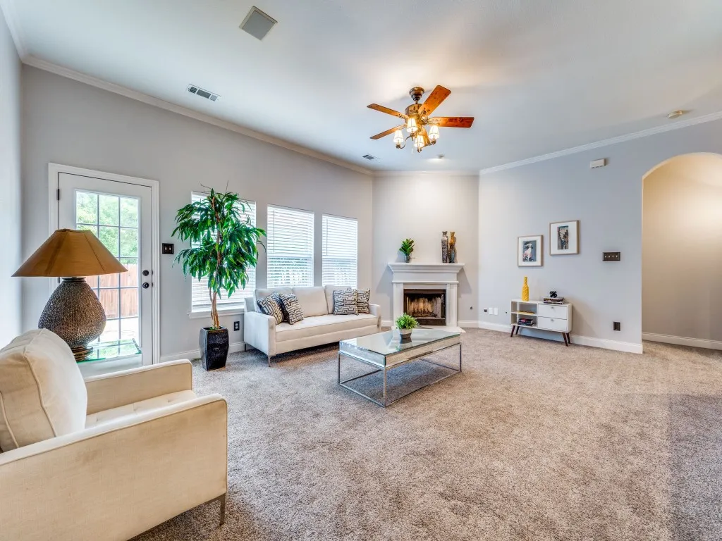 Spacious living area featuring high ceilings, crown molding, a built-in fireplace, multiple windows with blinds, and an arched entry