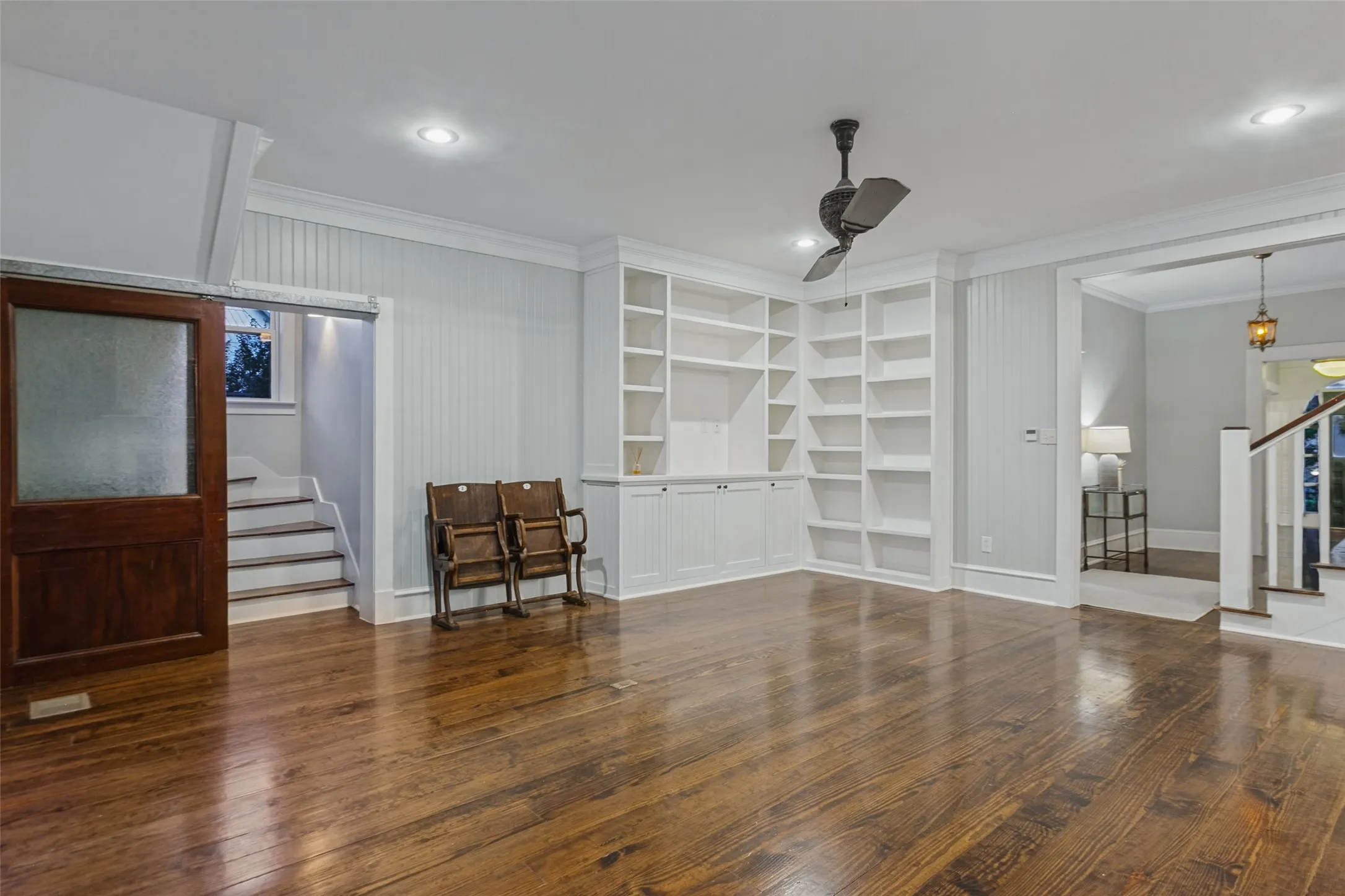 View of living room with built-in shelving, second staircase leading to primary bedroom
