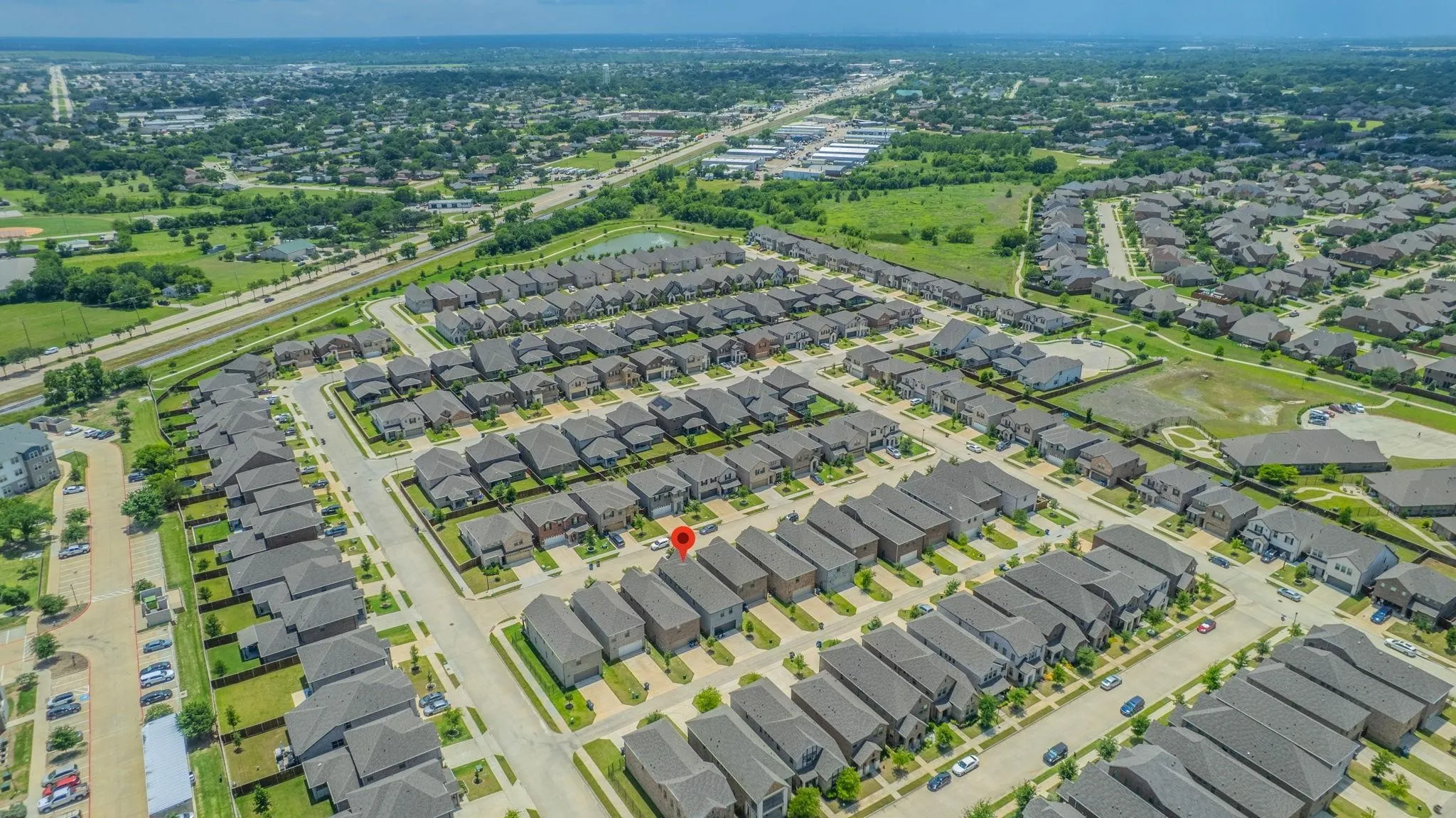 Aerial perspective of a developed residential community with uniform rooflines and landscaped properties