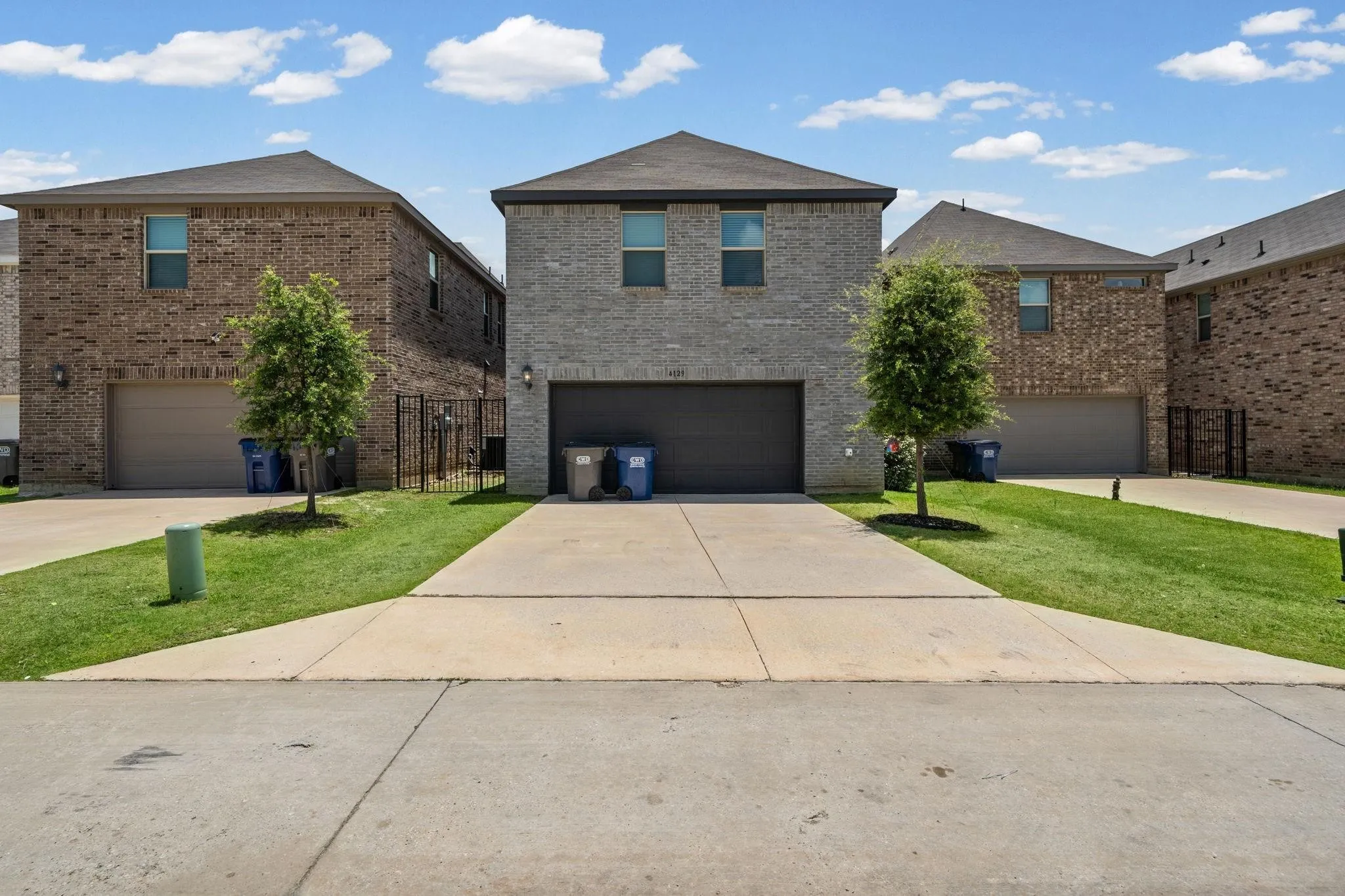 Two-story brick exterior with an attached garage, featuring a concrete driveway and a manicured lawn