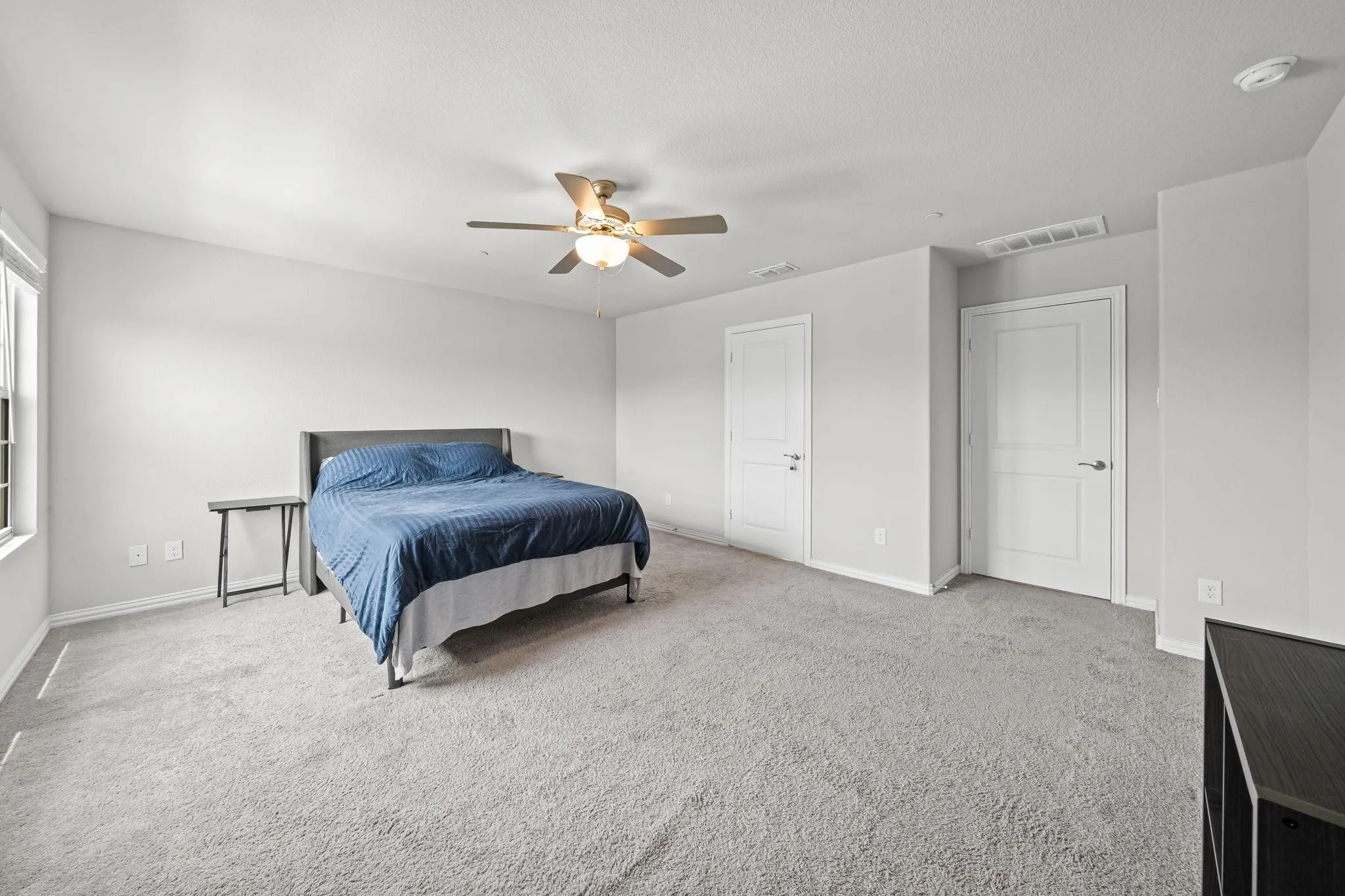 Light-colored carpeted flooring, white interior doors, and a ceiling fan with integrated lighting