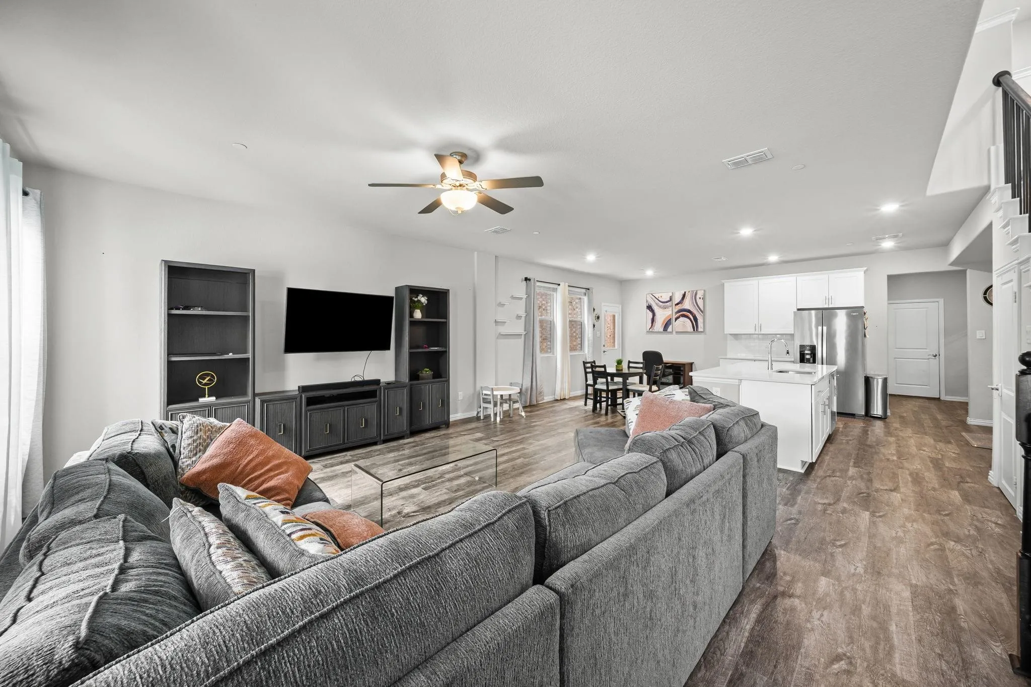 Open-concept living space with wood-finish flooring, recessed lighting, and a ceiling fan