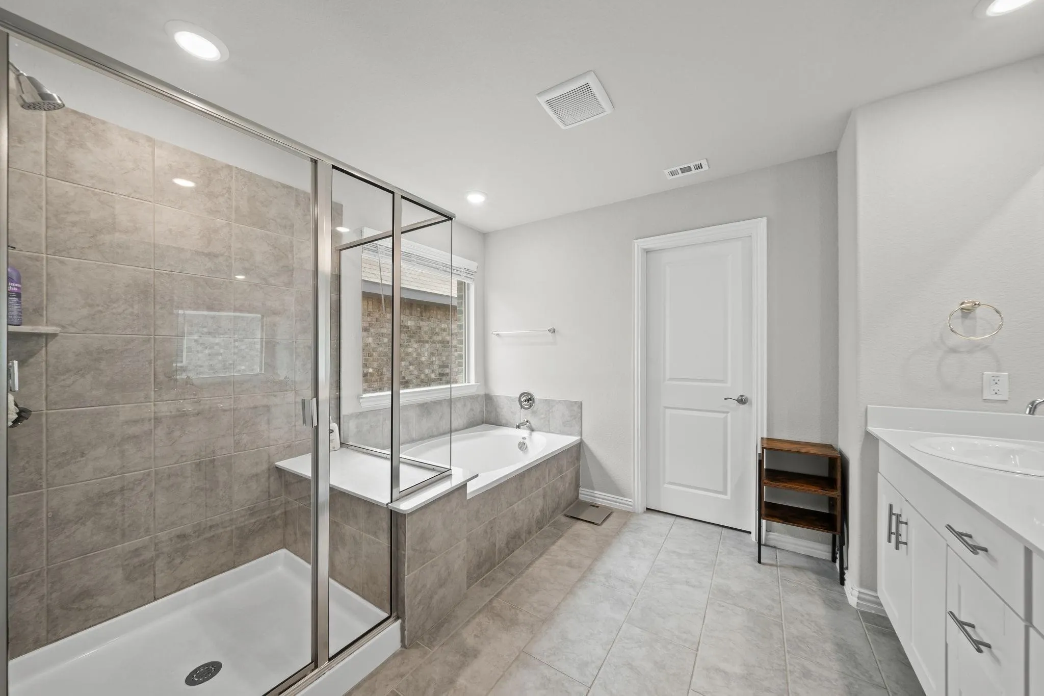 Contemporary bathroom featuring a glass-enclosed shower with tiled walls, a separate built-in bathtub, and a dual-sink vanity with white cabinetry