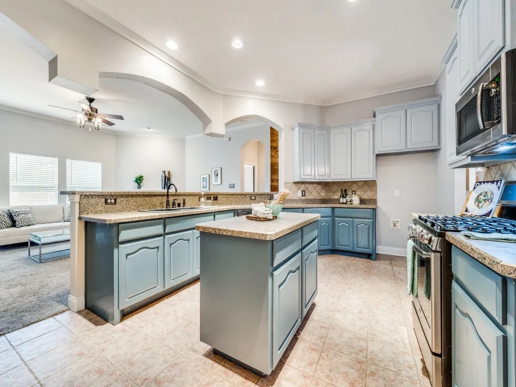 Kitchen featuring blue cabinetry, a central island, stainless steel appliances, and tile flooring