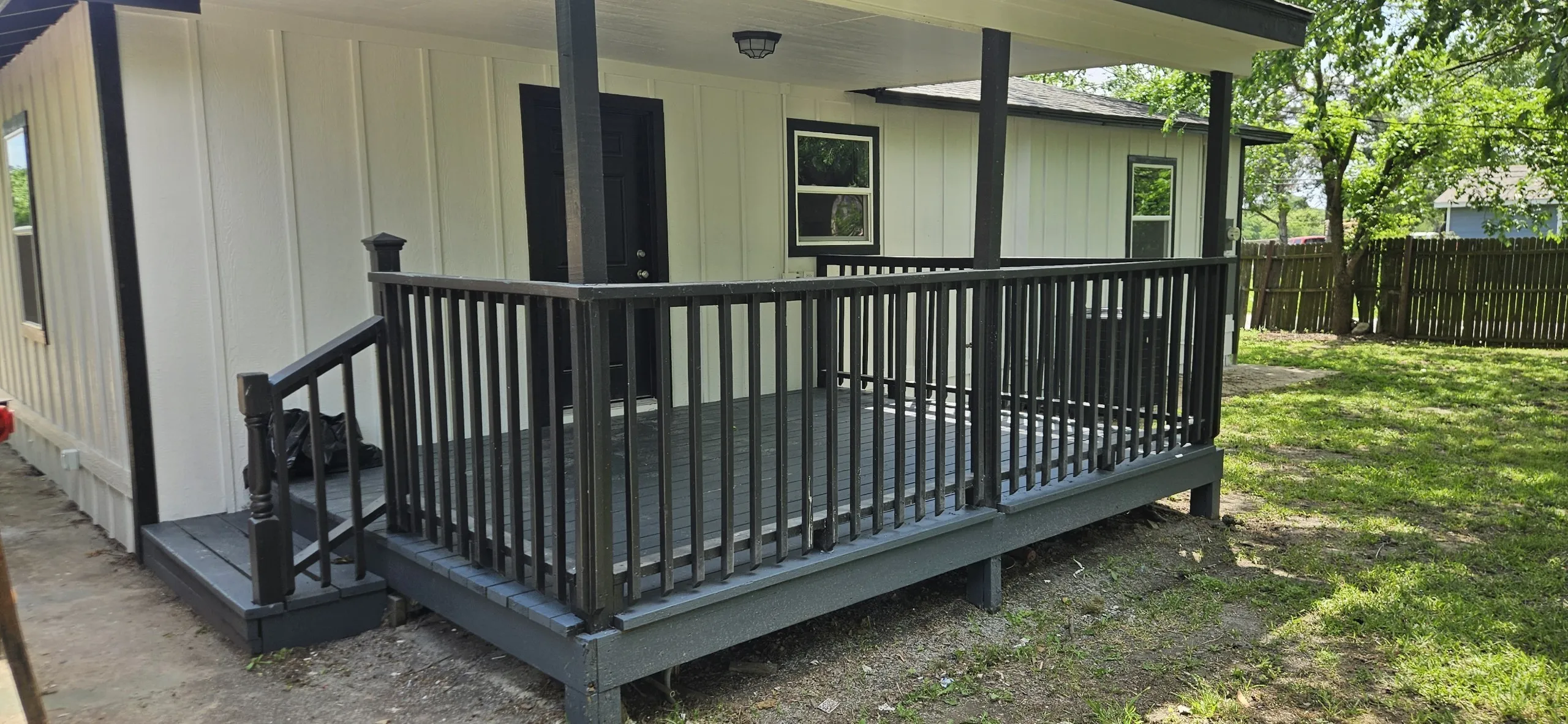 Expansive covered deck with dark railings, exterior lighting, and a board and batten facade