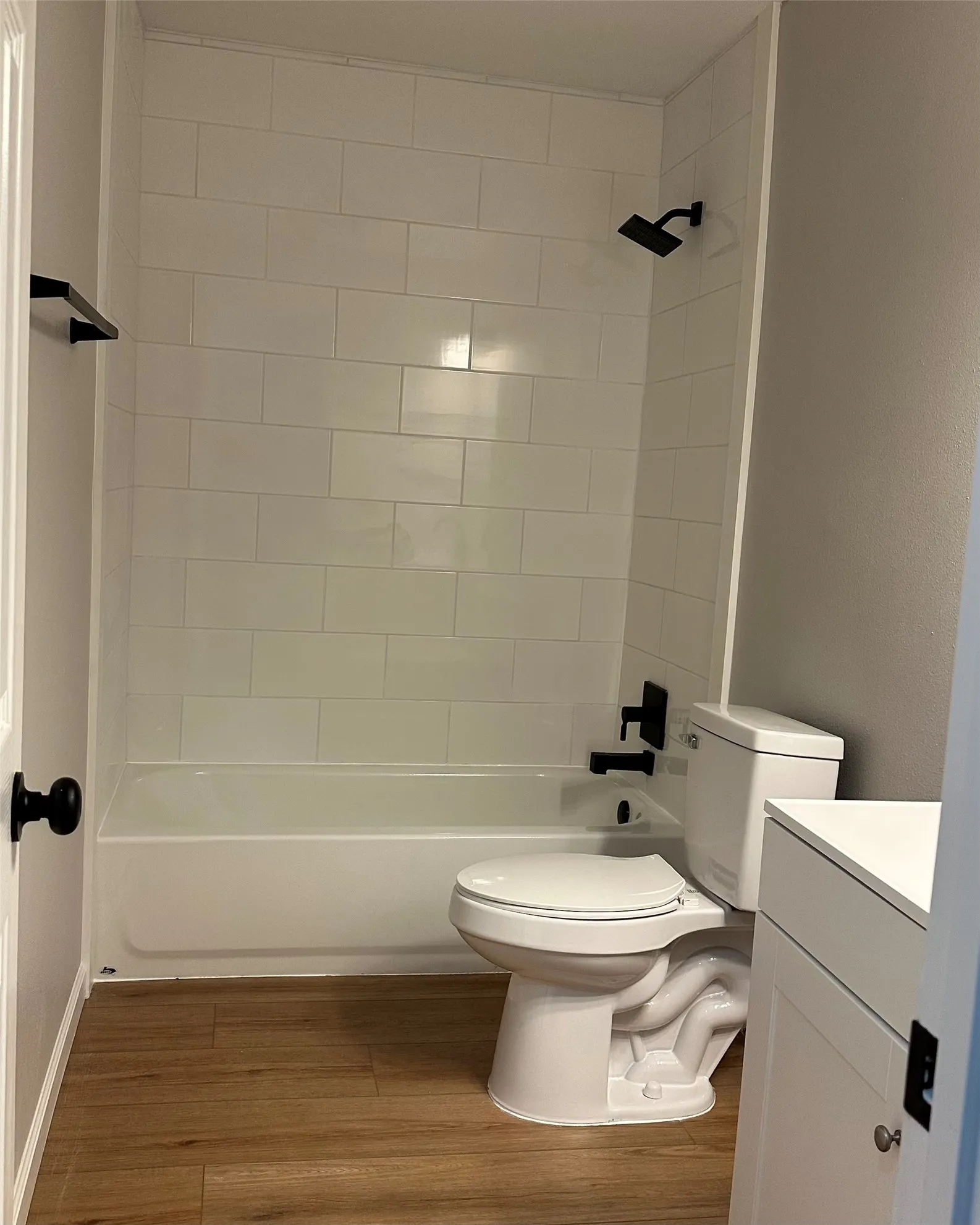 Bathtub and shower combination with subway tile surround, matte black showerhead, and matching fixtures