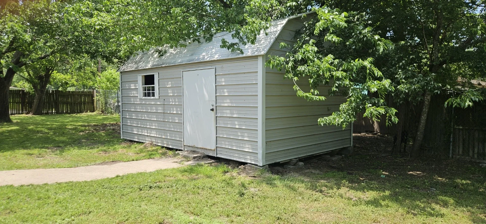 Detached utility shed featuring metal siding, a single entry door, and a single window