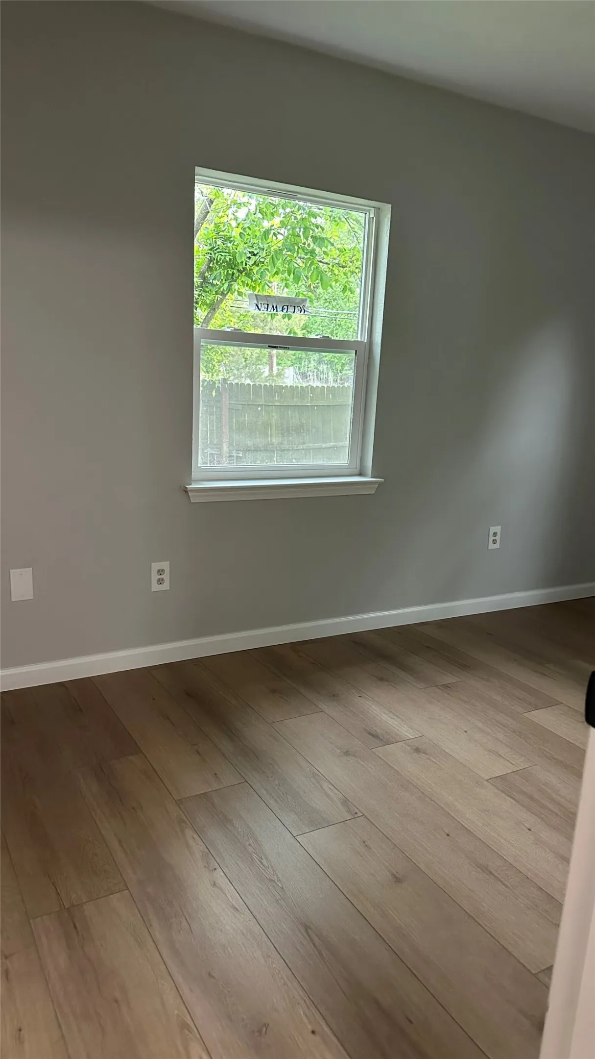 Wood-finish flooring with neutral wall tones and a single-pane window
